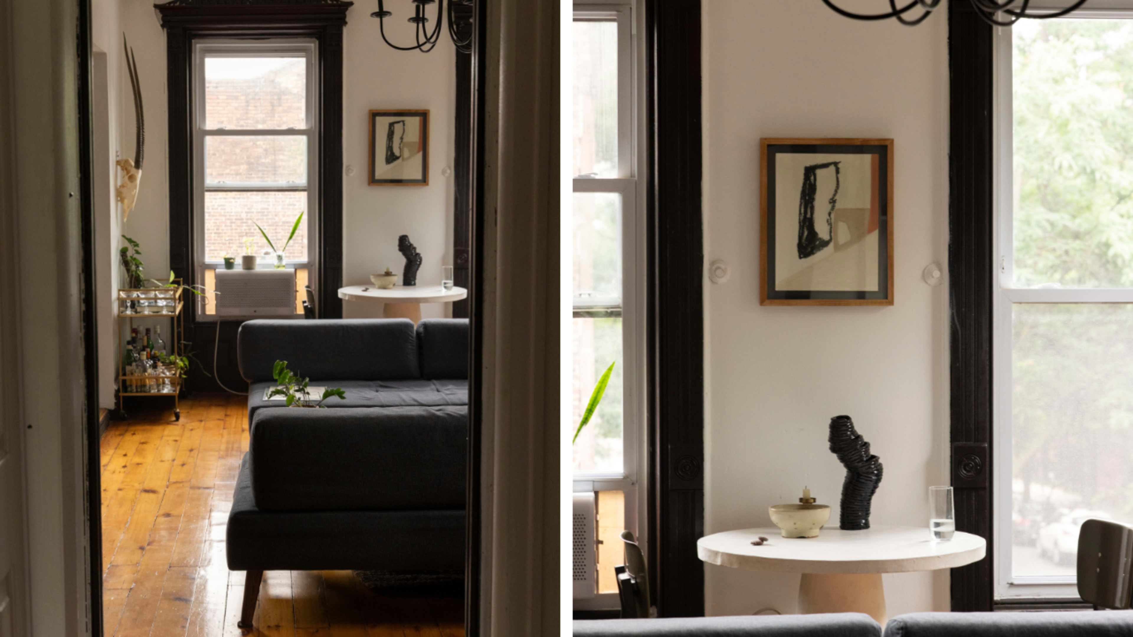 A narrow hallway connects a living room with a dark sofa and a small dining area featuring a white table and a sculptural piece.