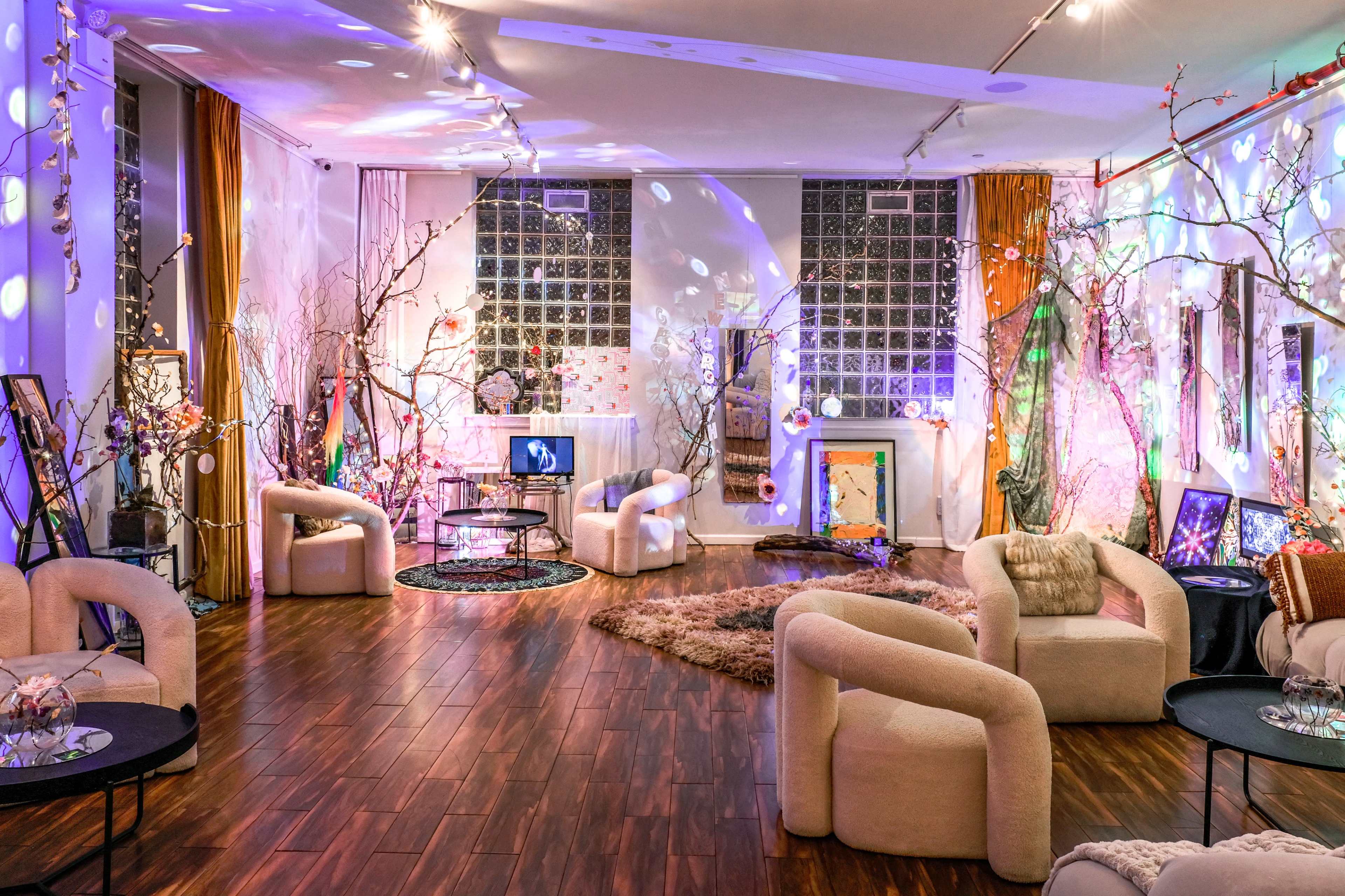 The image shows a spacious lounge area with plush furniture, decorative lighting, and artistic elements, creating a vibrant and inviting atmosphere.