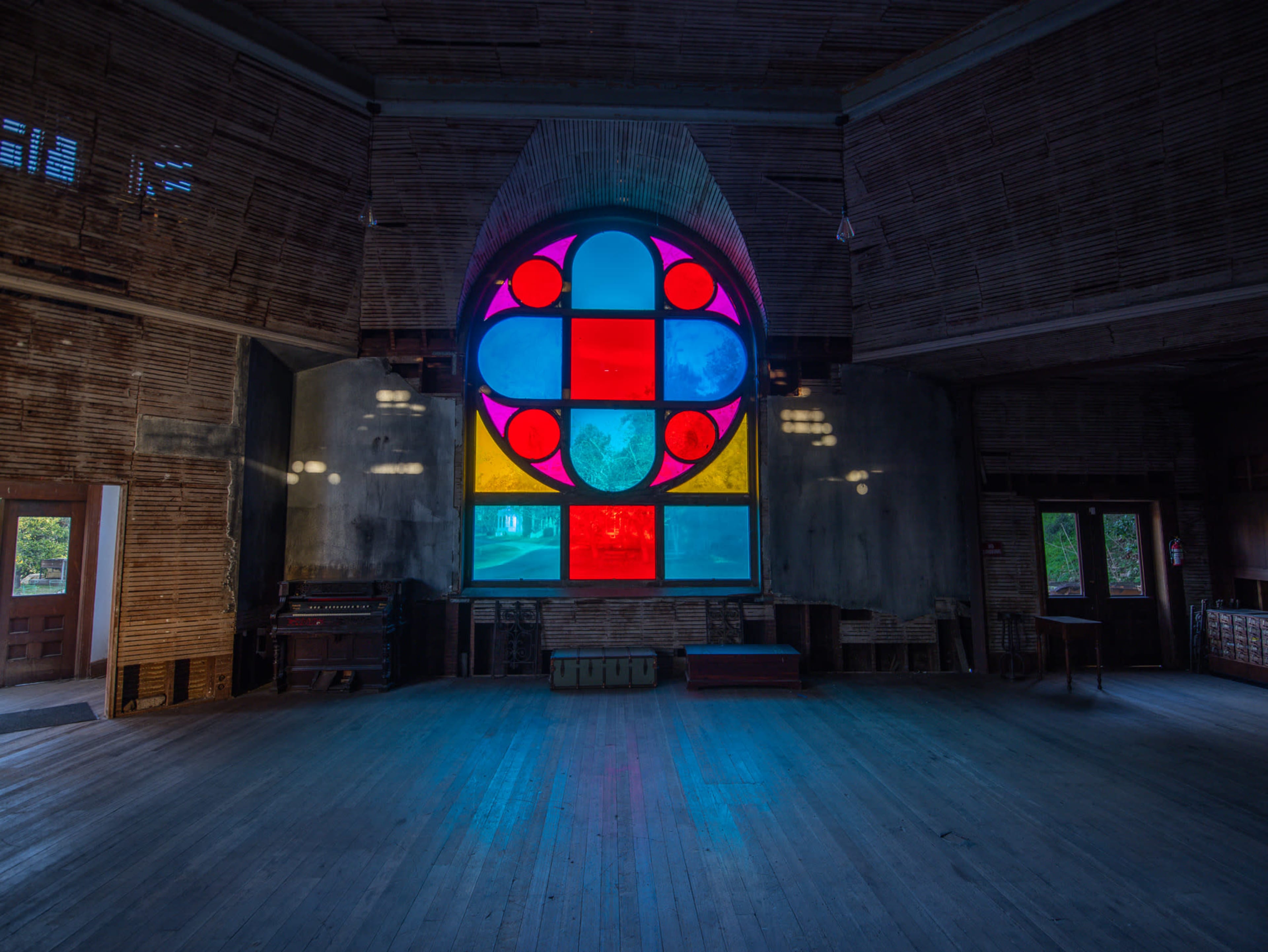 An interior space featuring a large stained glass window with geometric patterns in vibrant colors.