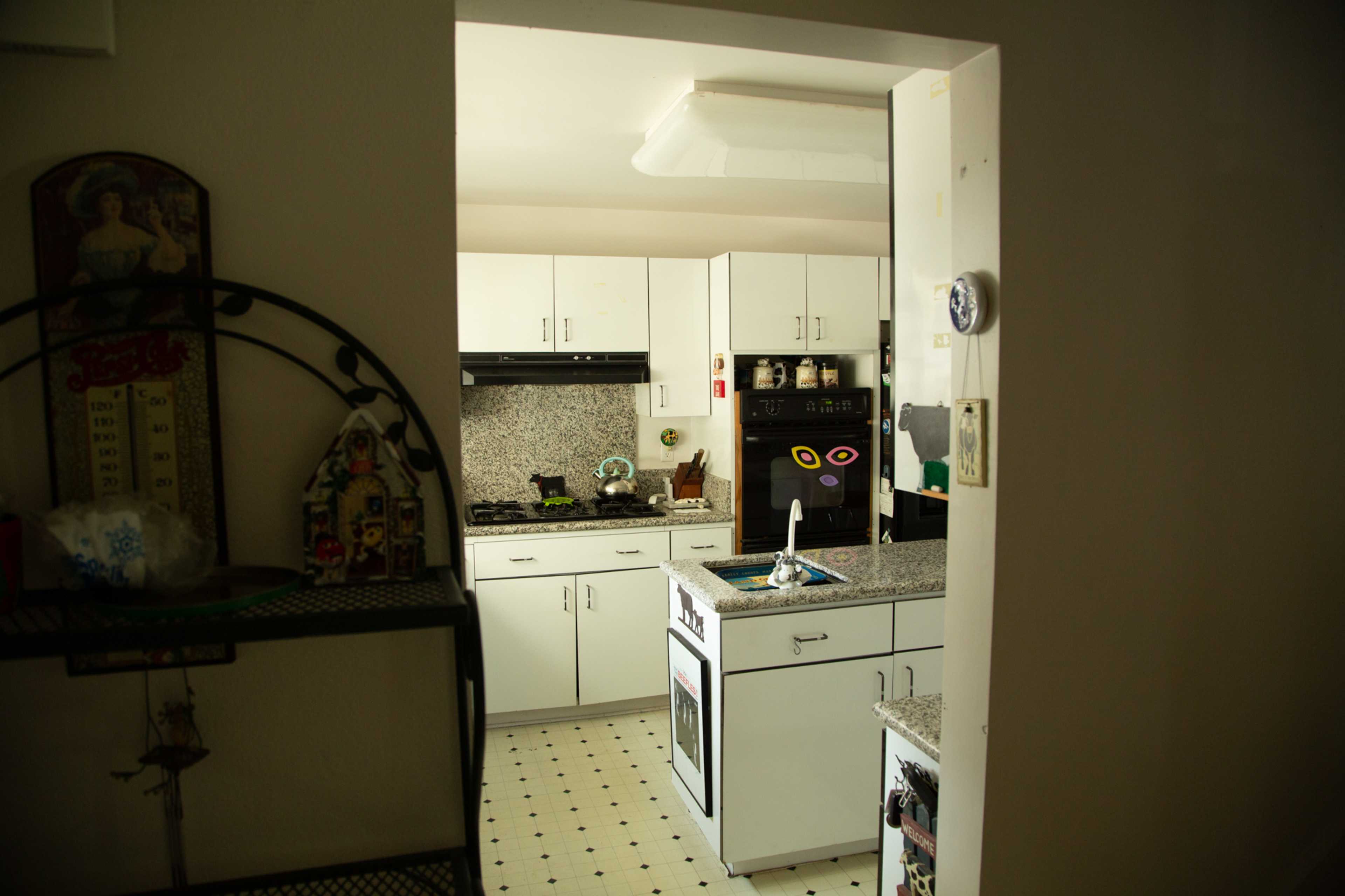 A view of a kitchen featuring white cabinets, a granite countertop, and appliances including a stove and an oven.