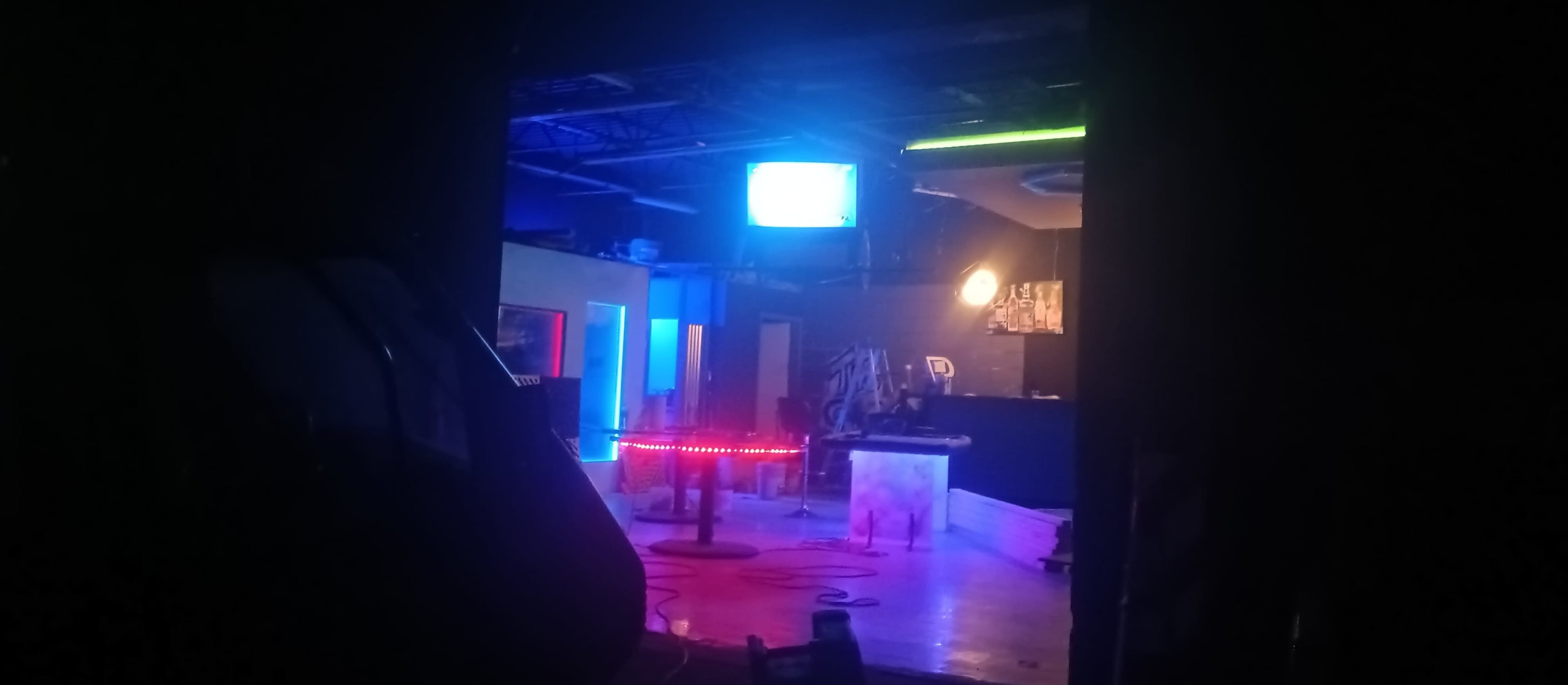 A dimly lit room with colorful neon lights and a vintage television screen displaying a blue image.