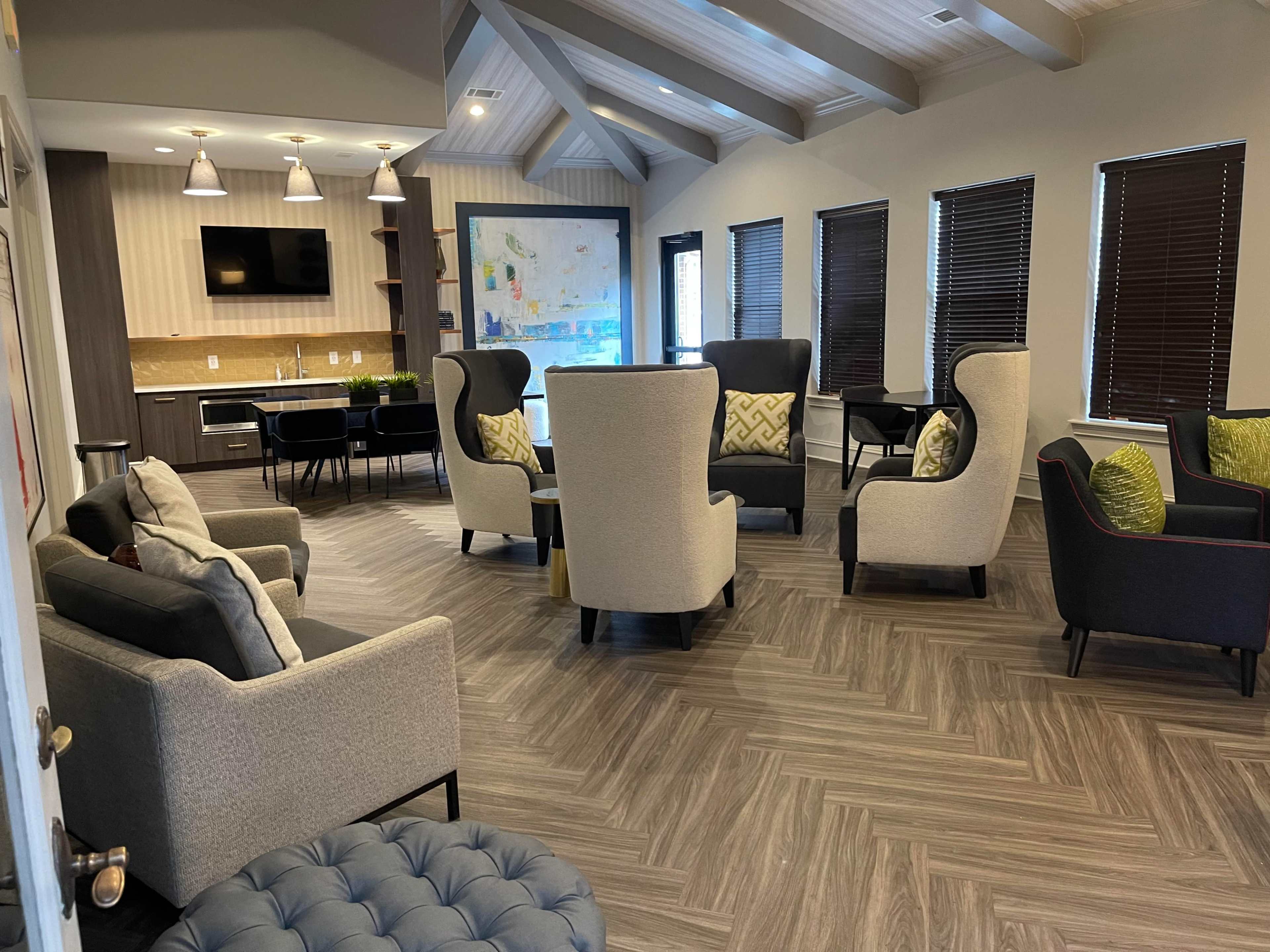 A modern lounge area with several upholstered chairs, a couch, and a kitchen space in the background, featuring a large map on the wall.