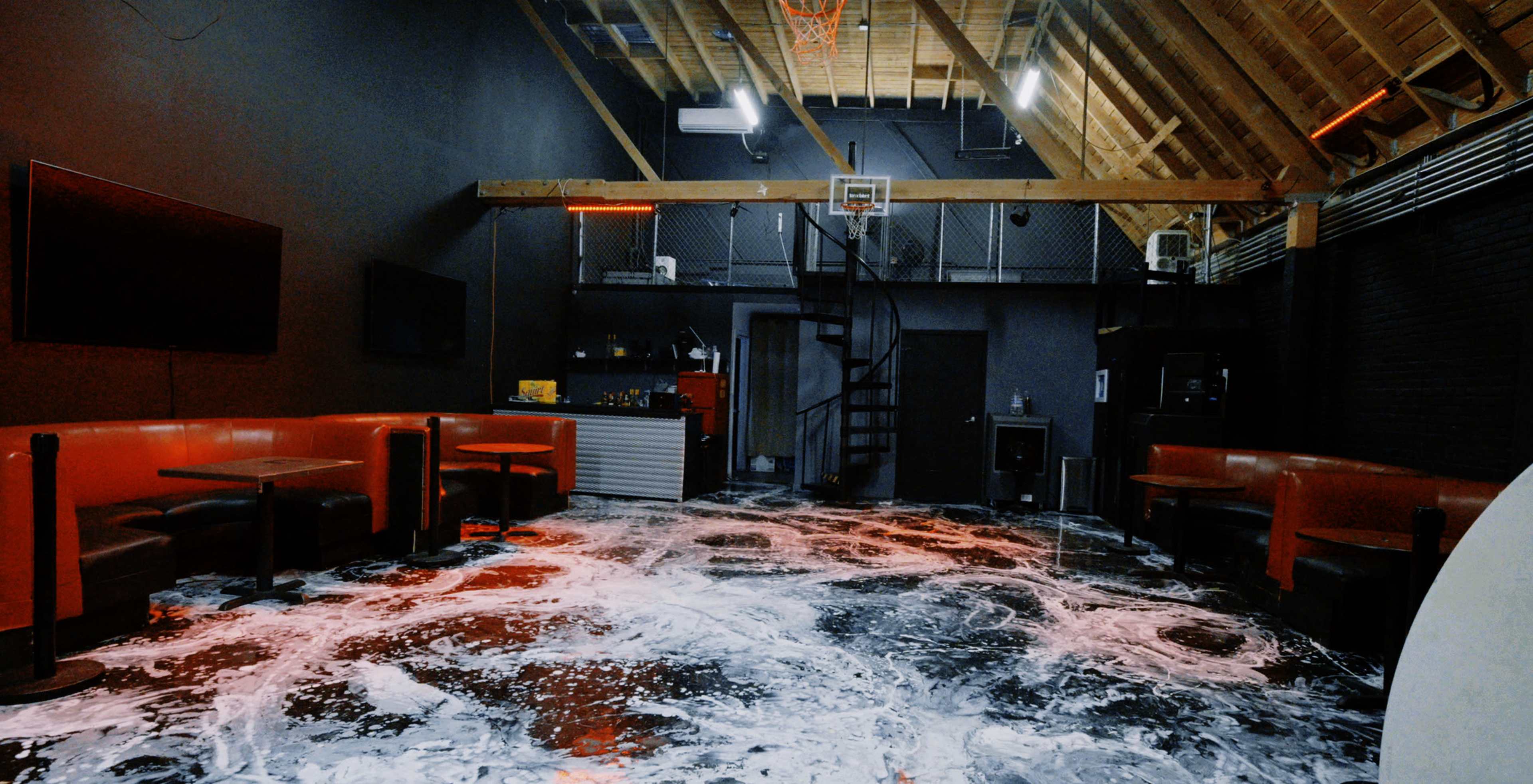 The image shows a large indoor space with red seating, a basketball hoop, and a floor covered in a foamy substance.