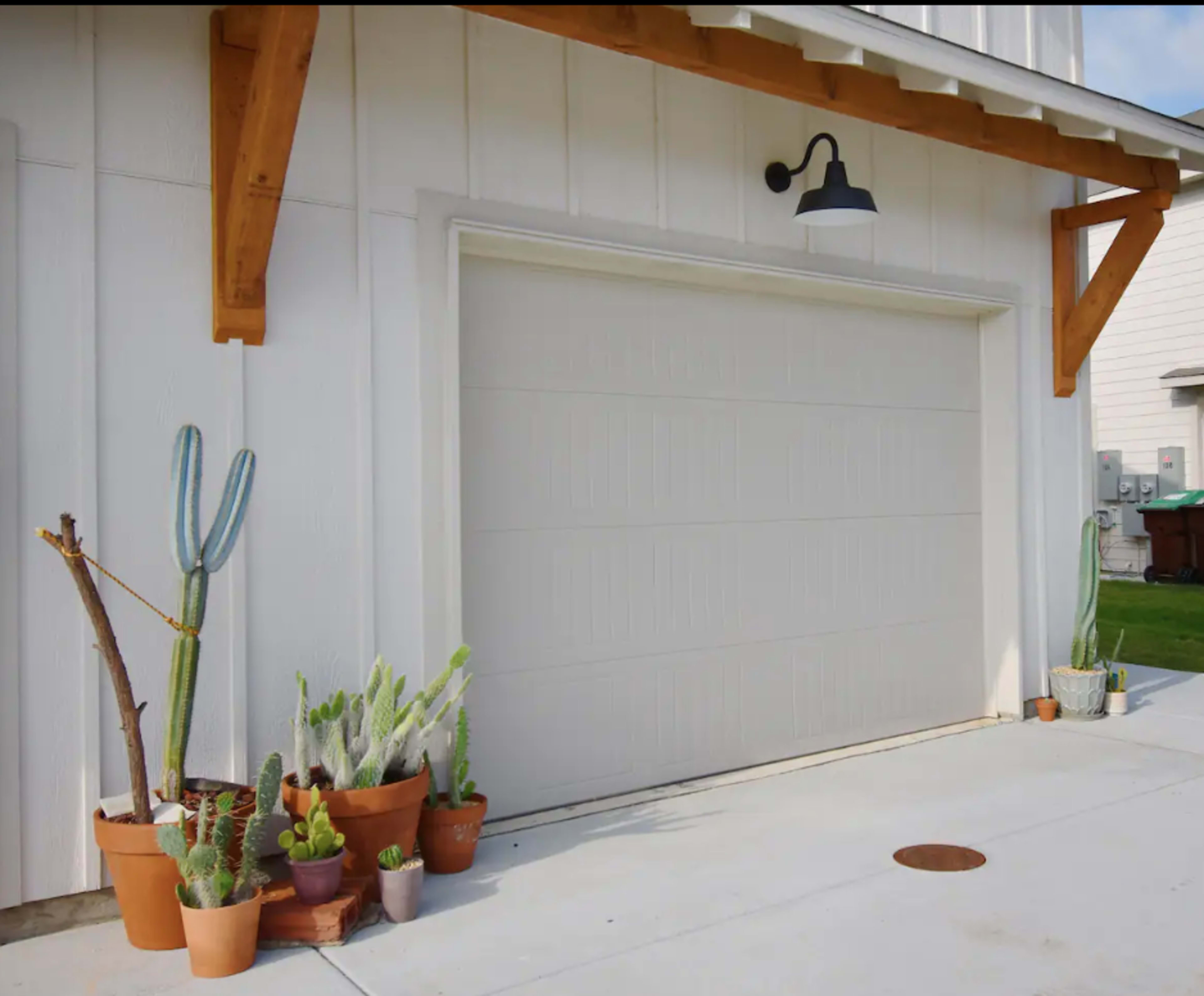 A garage door flanked by various potted cacti and succulents on a concrete surface.