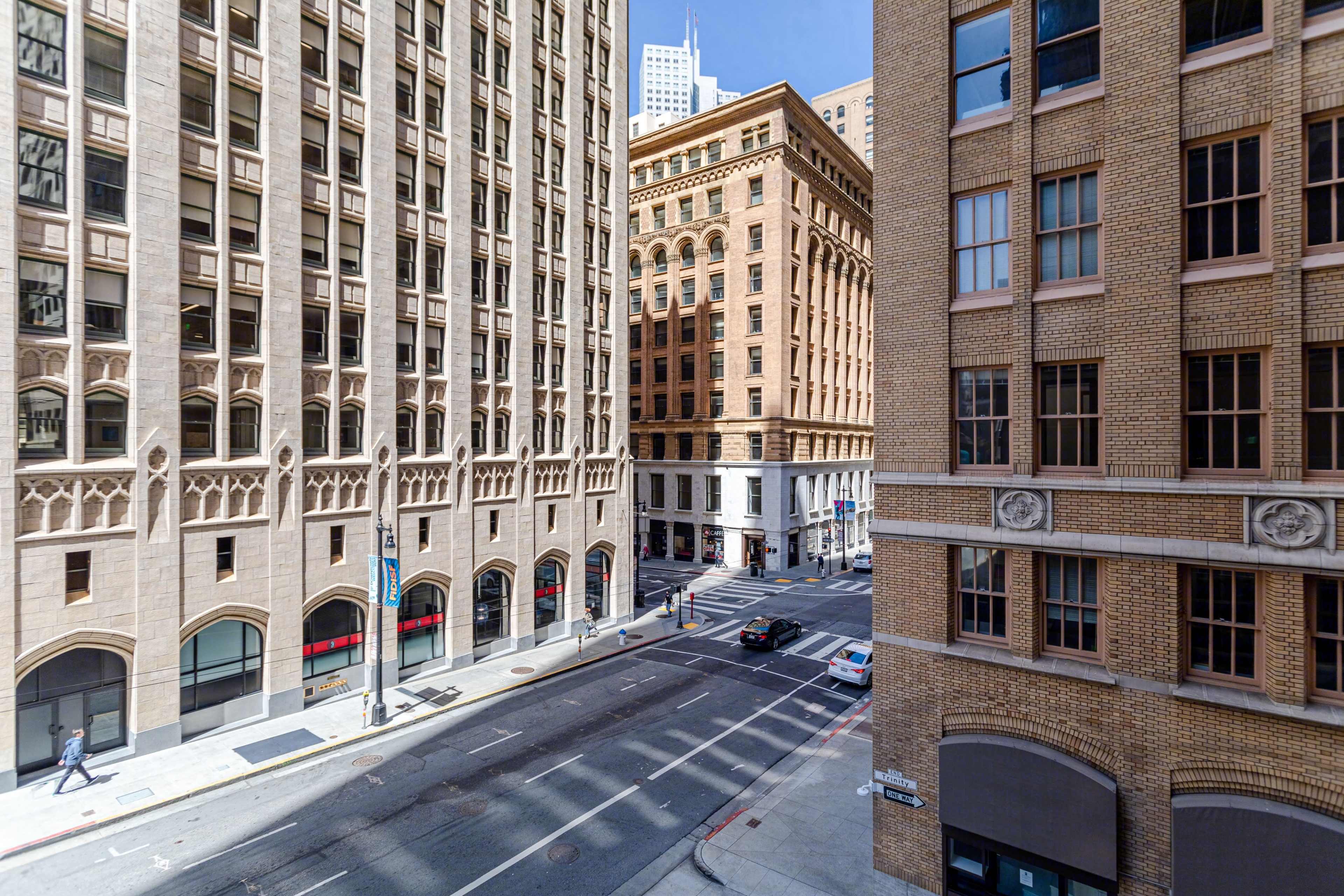 An intersection of city streets lined with tall buildings, featuring a mix of architectural styles.