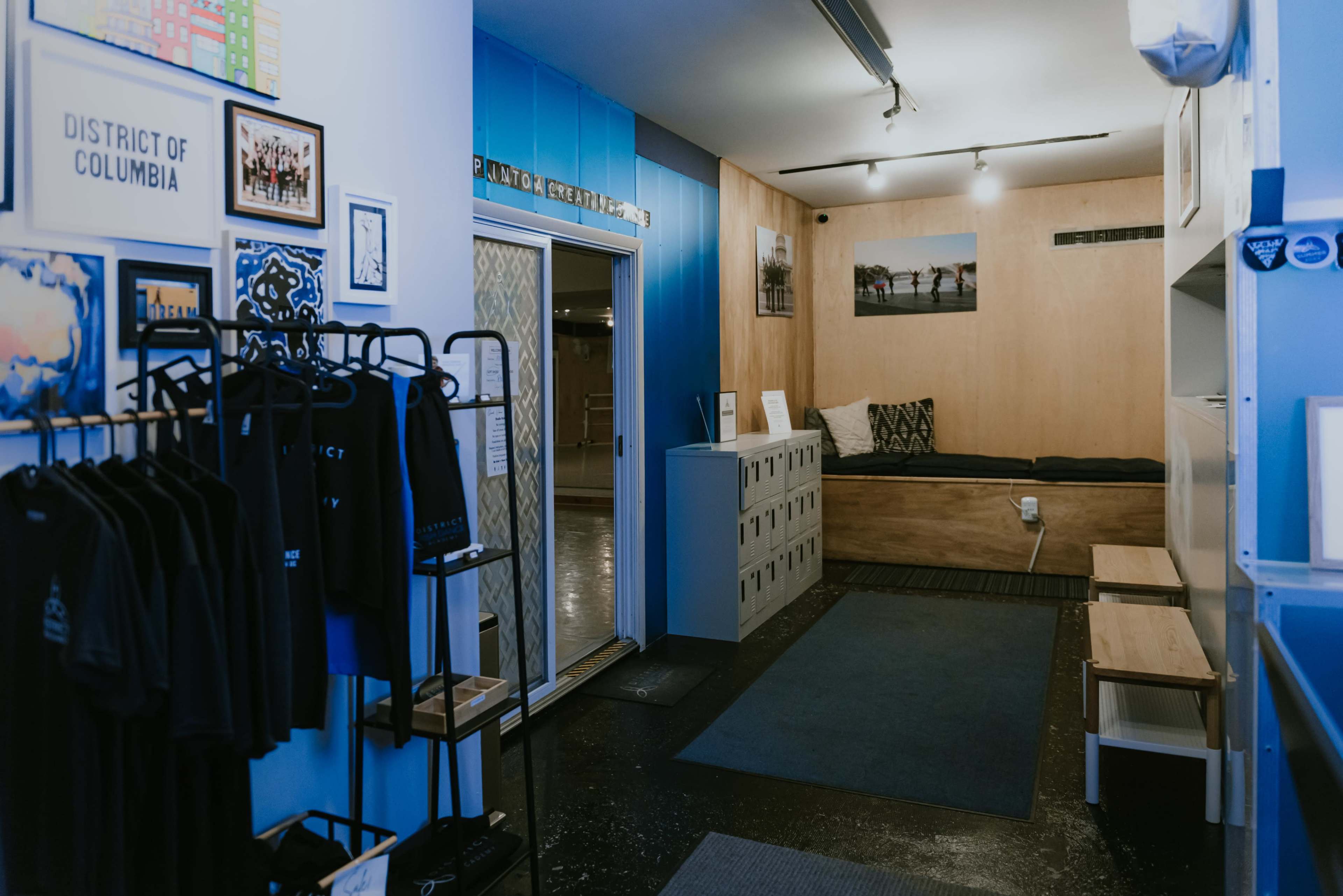 A minimalist interior space with a reception area featuring lockers, seating, and merchandise displays.
