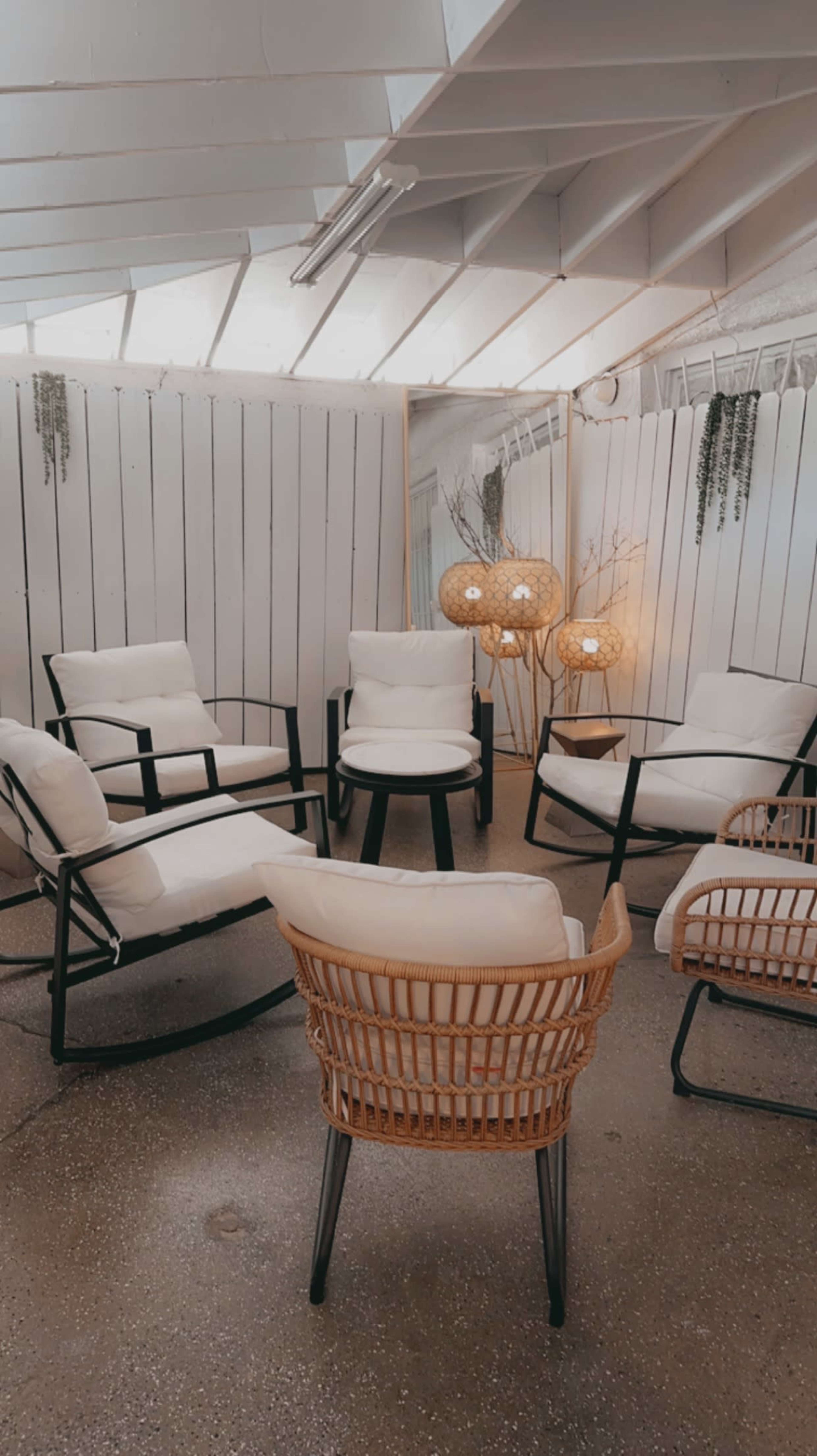 A cozy seating area features five chairs arranged around a central table, with decorative lighting and greenery in a softly lit room.