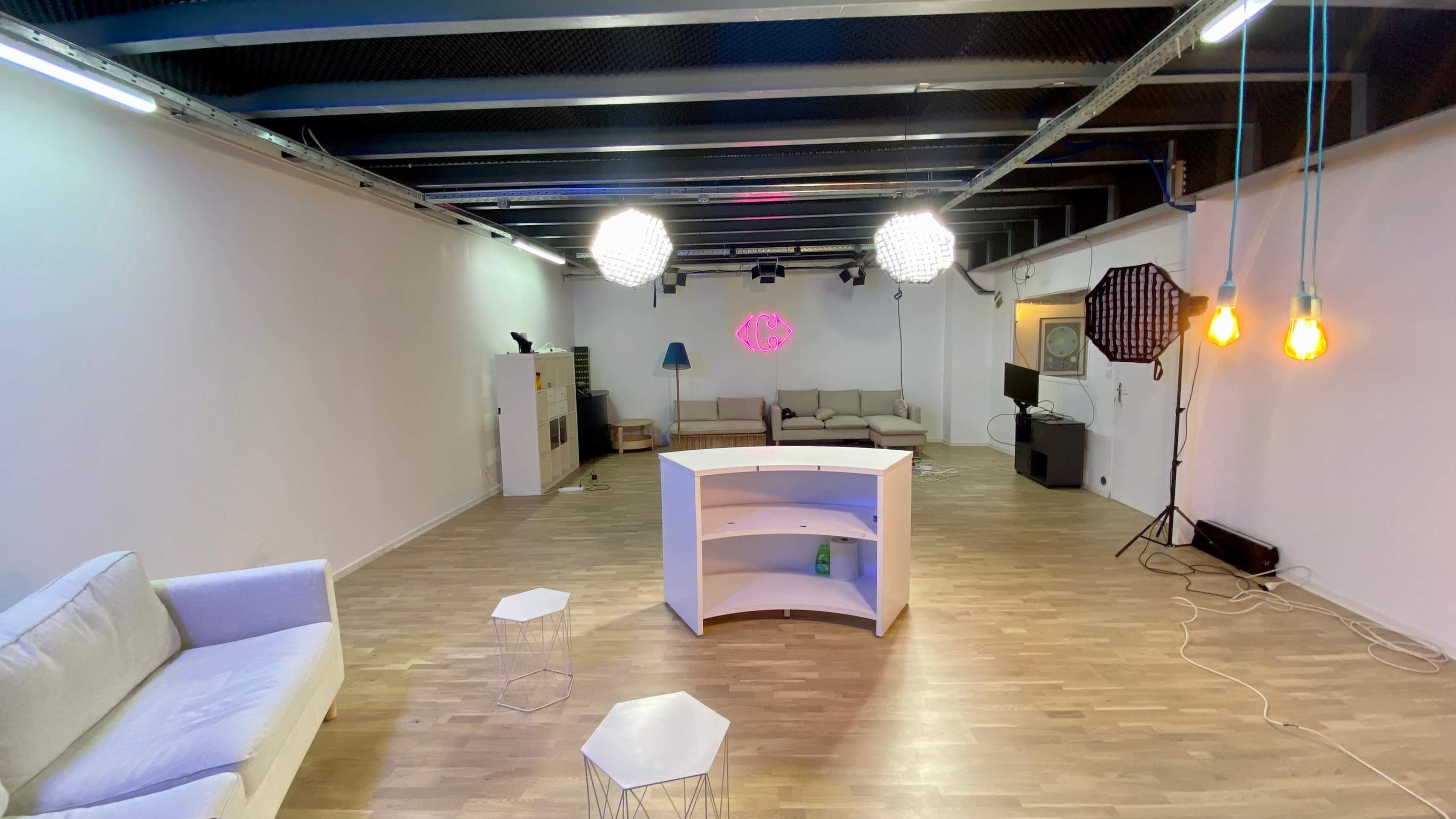 A spacious, well-lit room with a sectional sofa, a small table, a television, and decorative lighting.