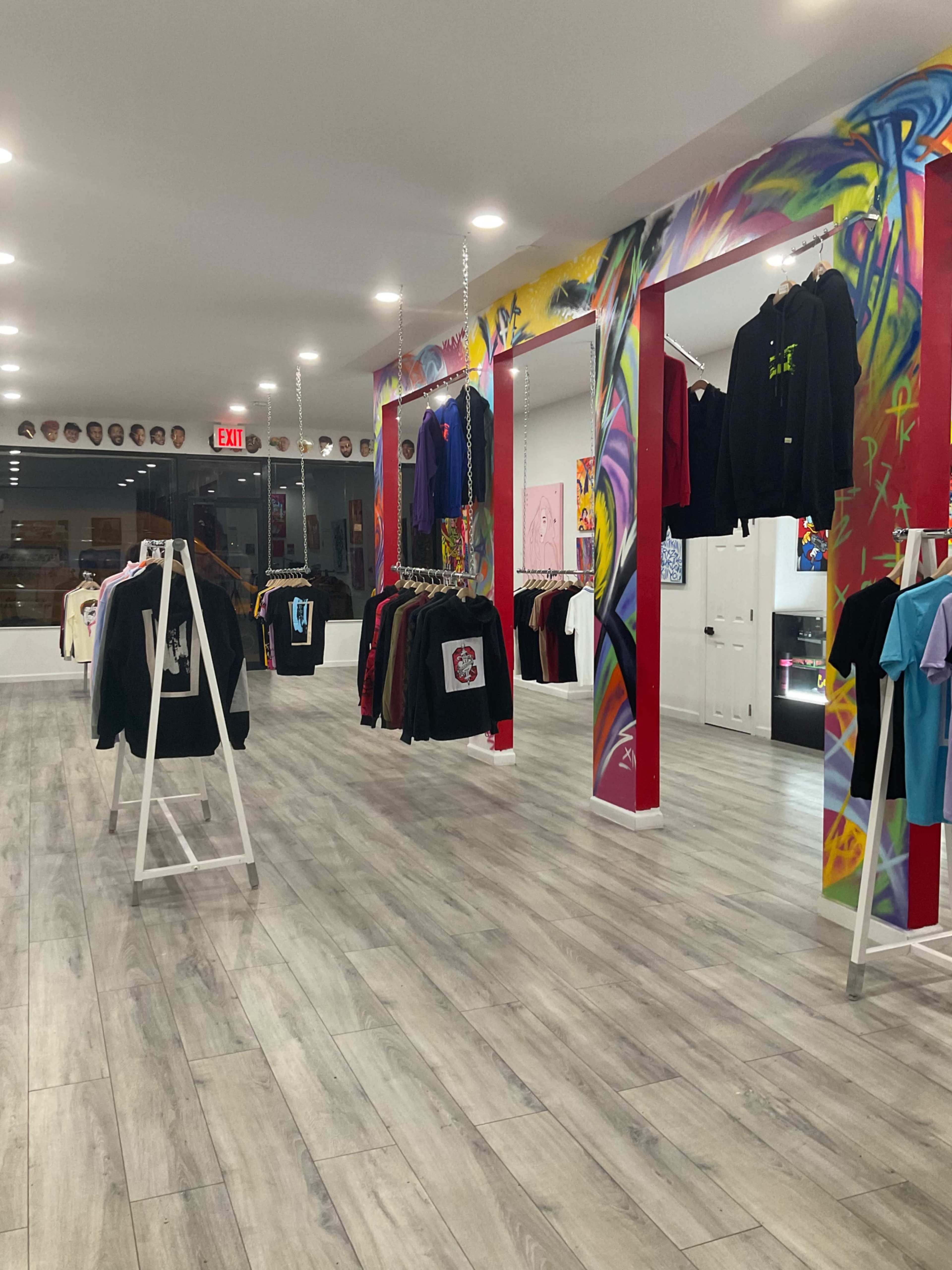 An apparel store featuring various hanging garments on racks and vibrant mural designs on the walls.