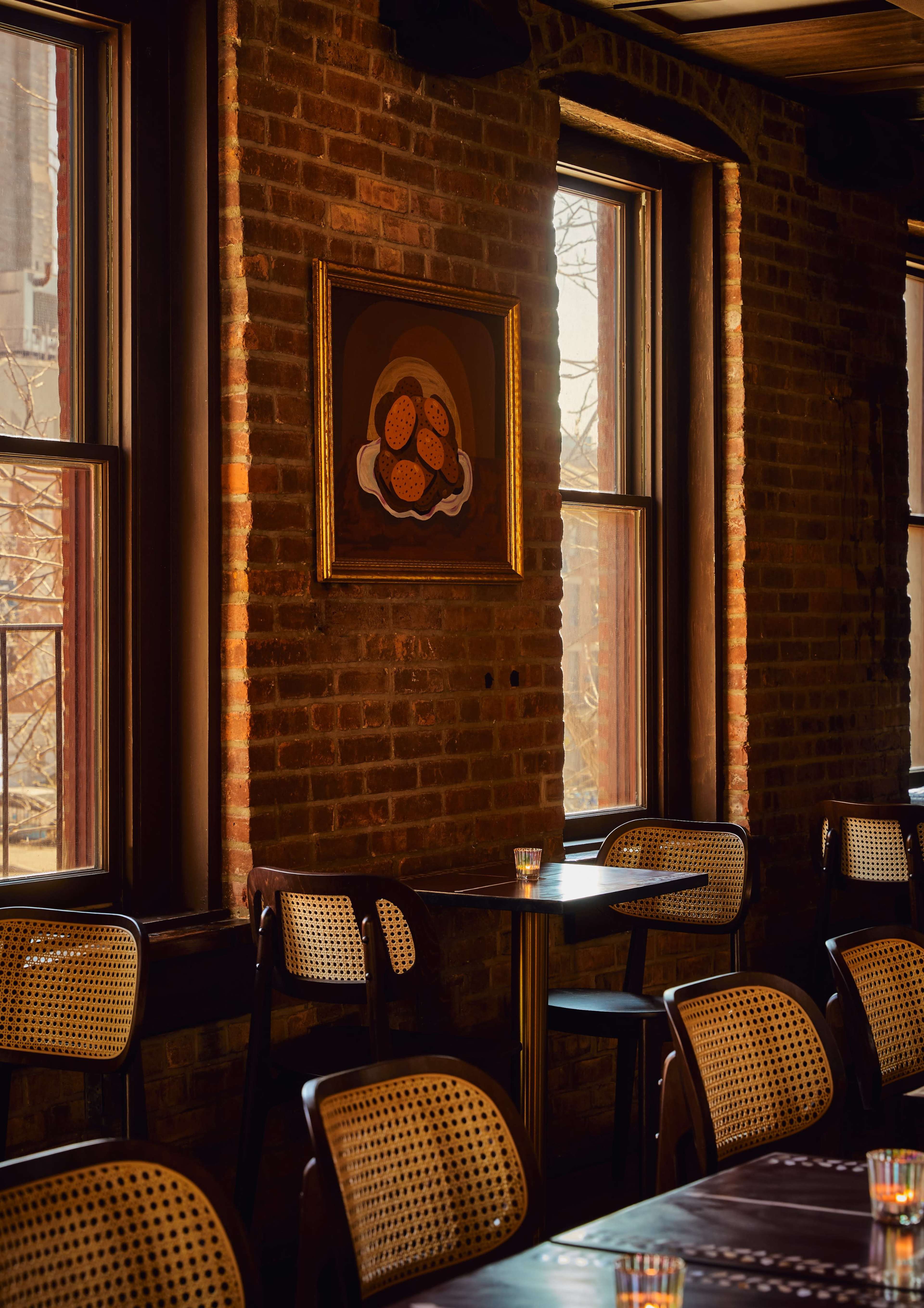 The scene features a dimly lit restaurant with wooden tables and chairs, exposed brick walls, and artwork hanging near the windows.