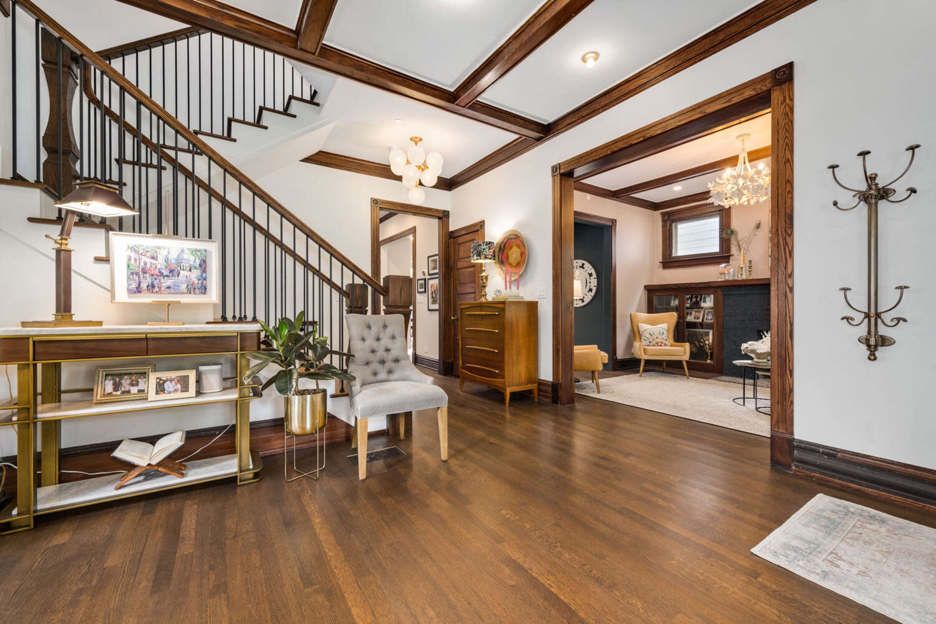 An entryway with a staircase, wooden accents, and a seating area leading into a living room.