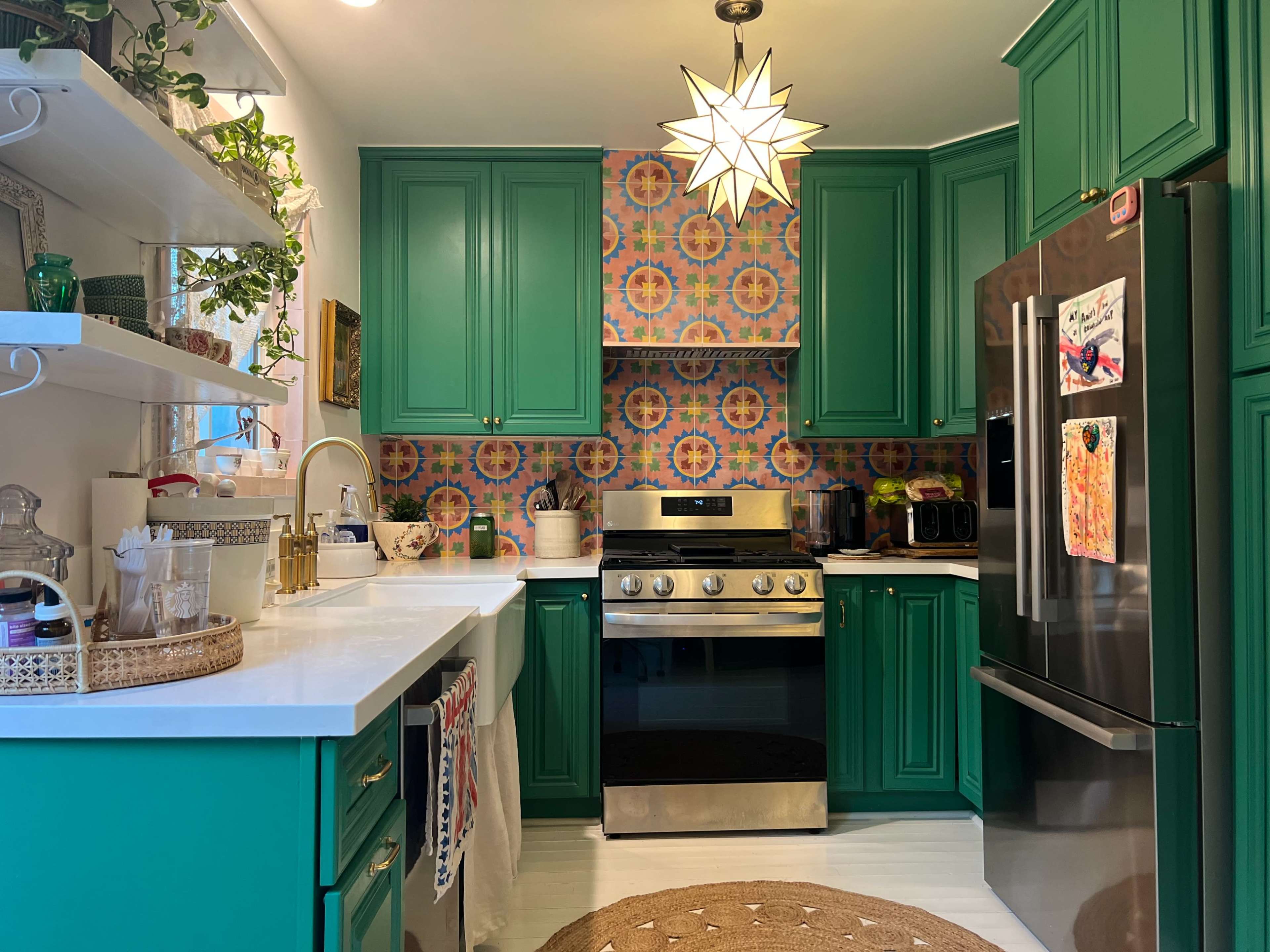 The kitchen features green cabinetry, a stainless steel stove, and patterned tile backsplash, with natural light coming through a window.