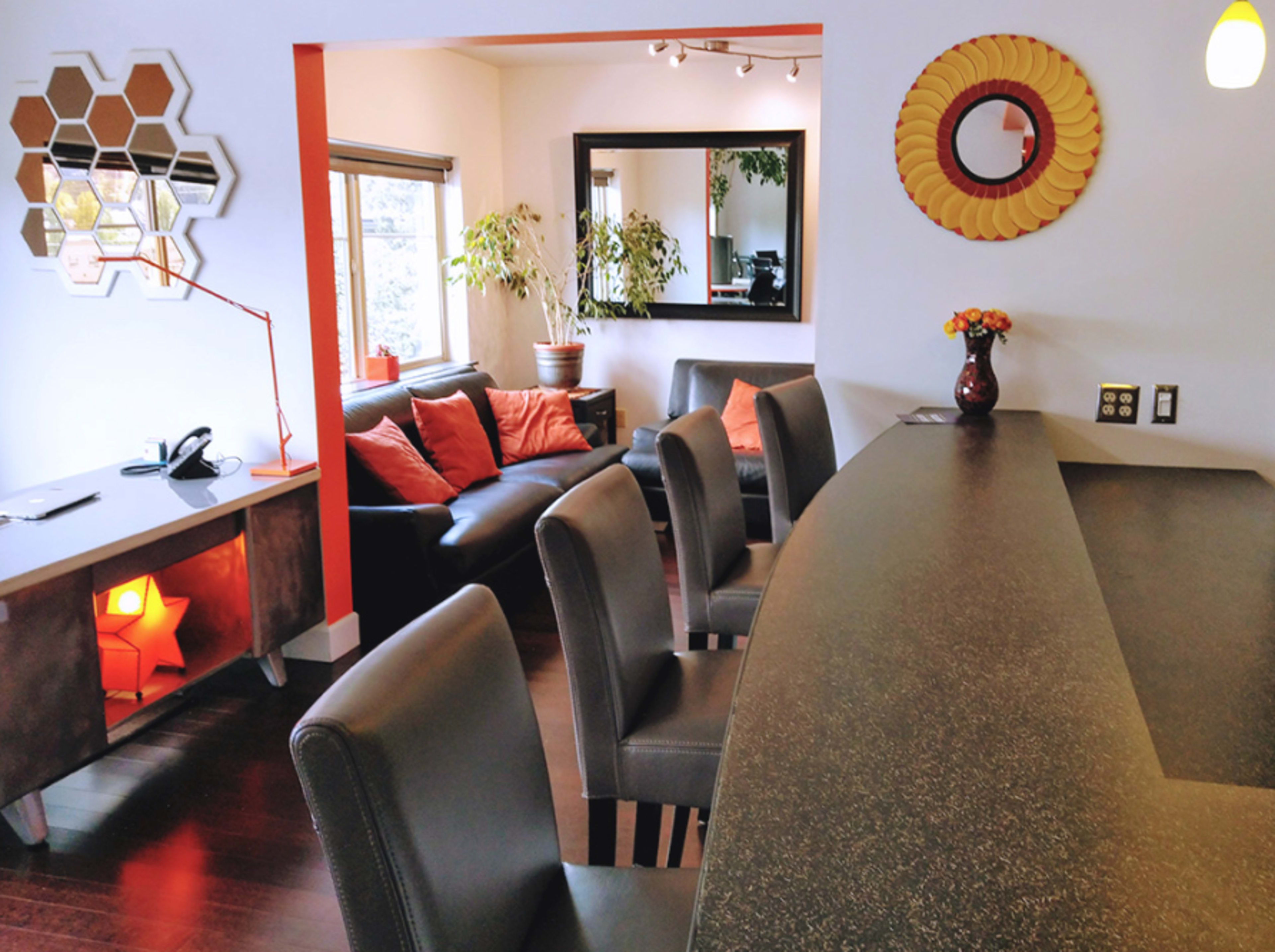 A modern living space featuring a bar area with high stools, a sofa, and decorative elements like plants and wall art.