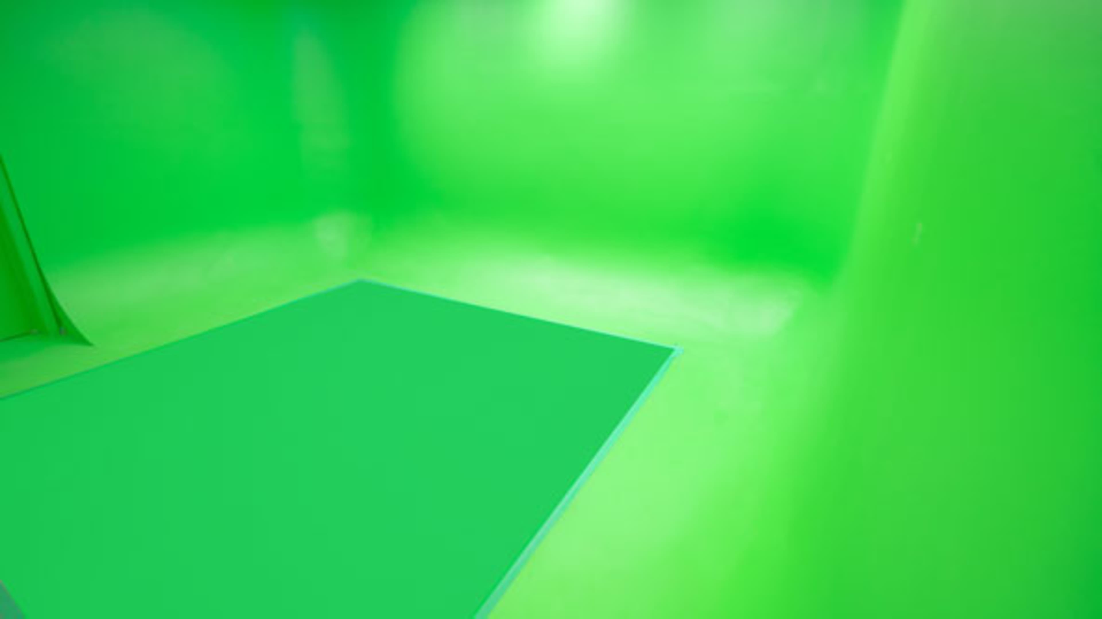 The image shows a room with green walls and a green floor area, commonly used for chroma key effects in video production.