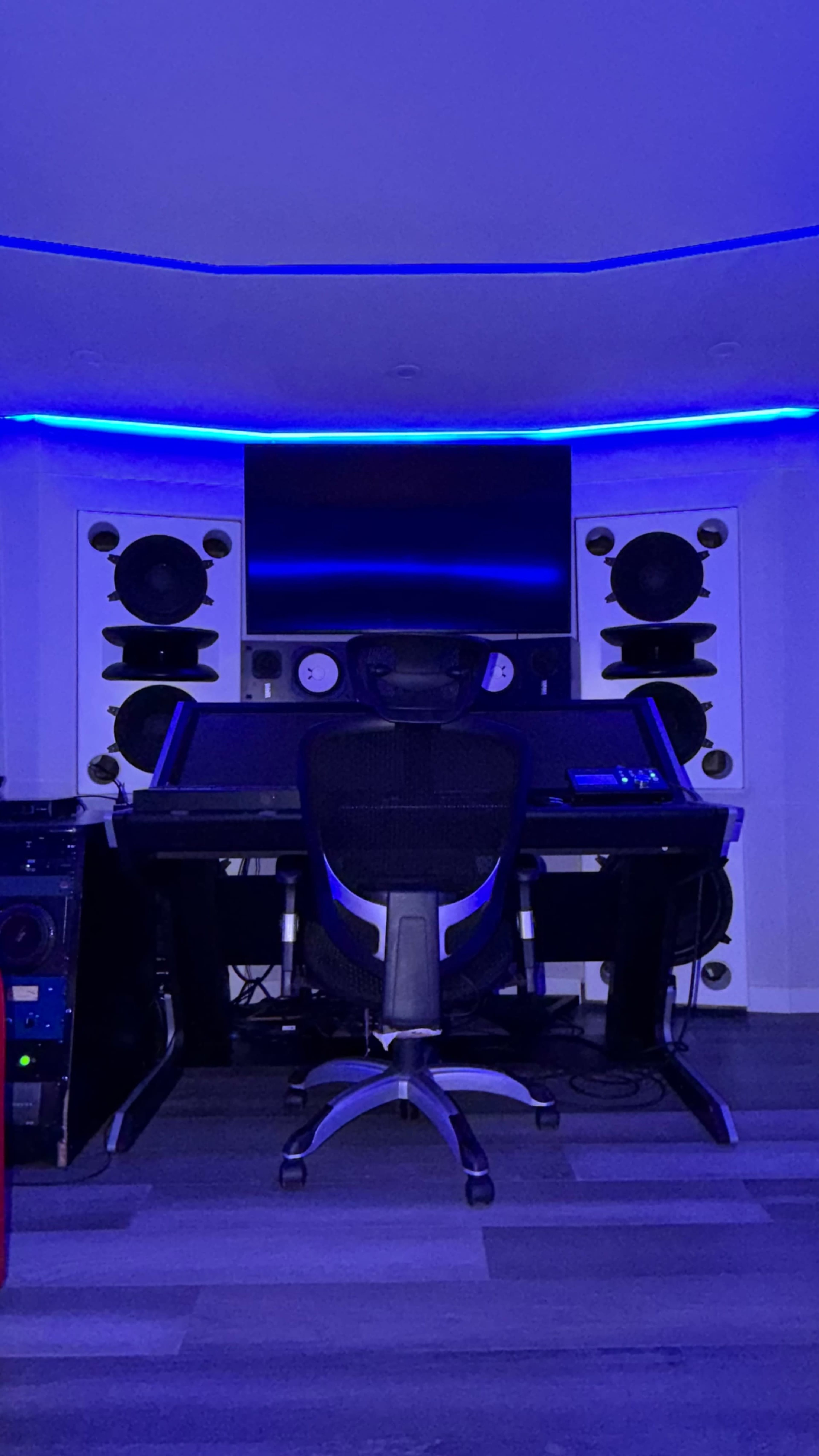 The image features a modern music studio with a large desk, computer monitor, and multiple speakers, all illuminated by blue LED lighting.