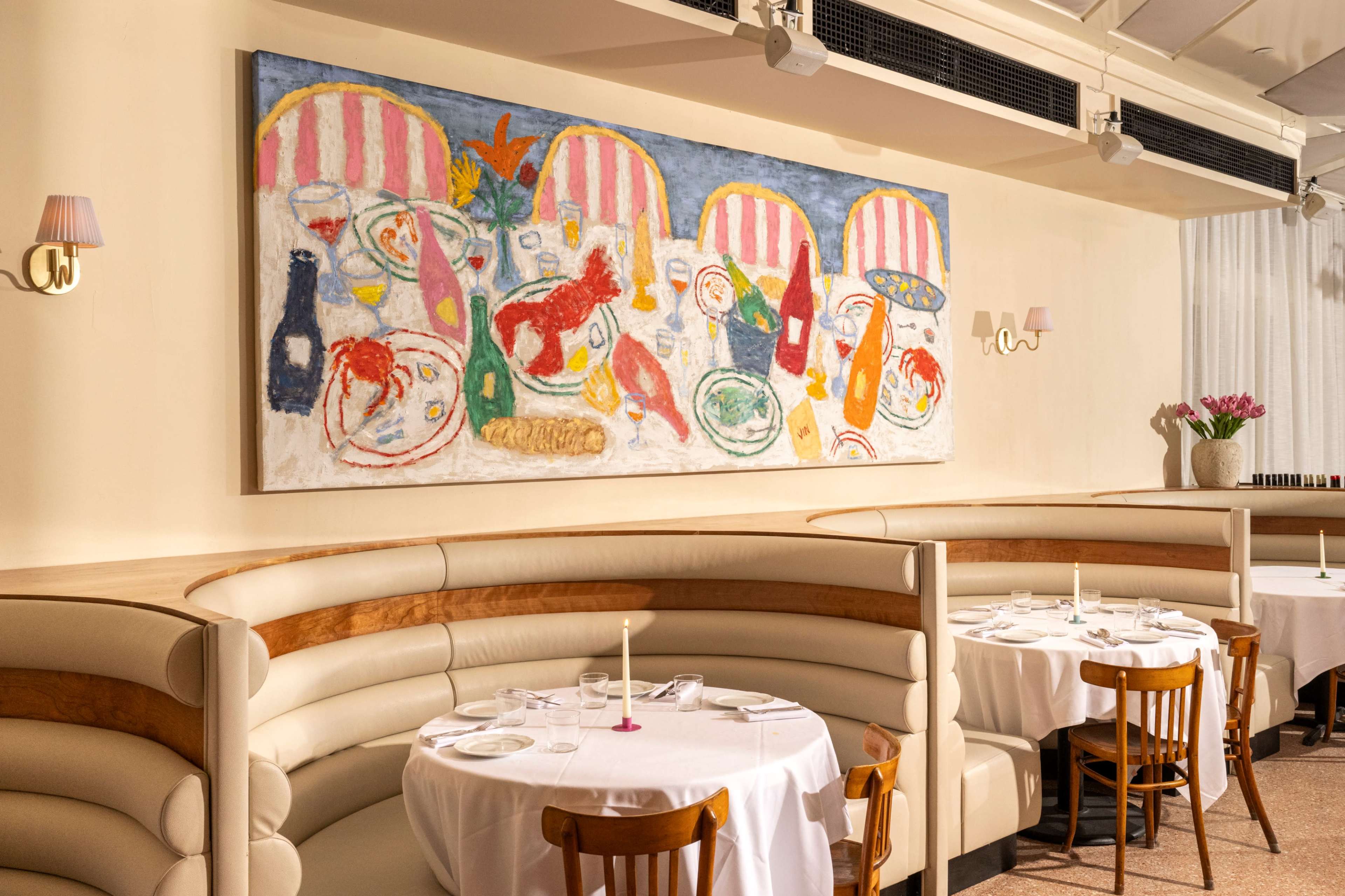 The image depicts a restaurant interior with curved booths, white tablecloths, and a large colorful painting hanging on the wall above.