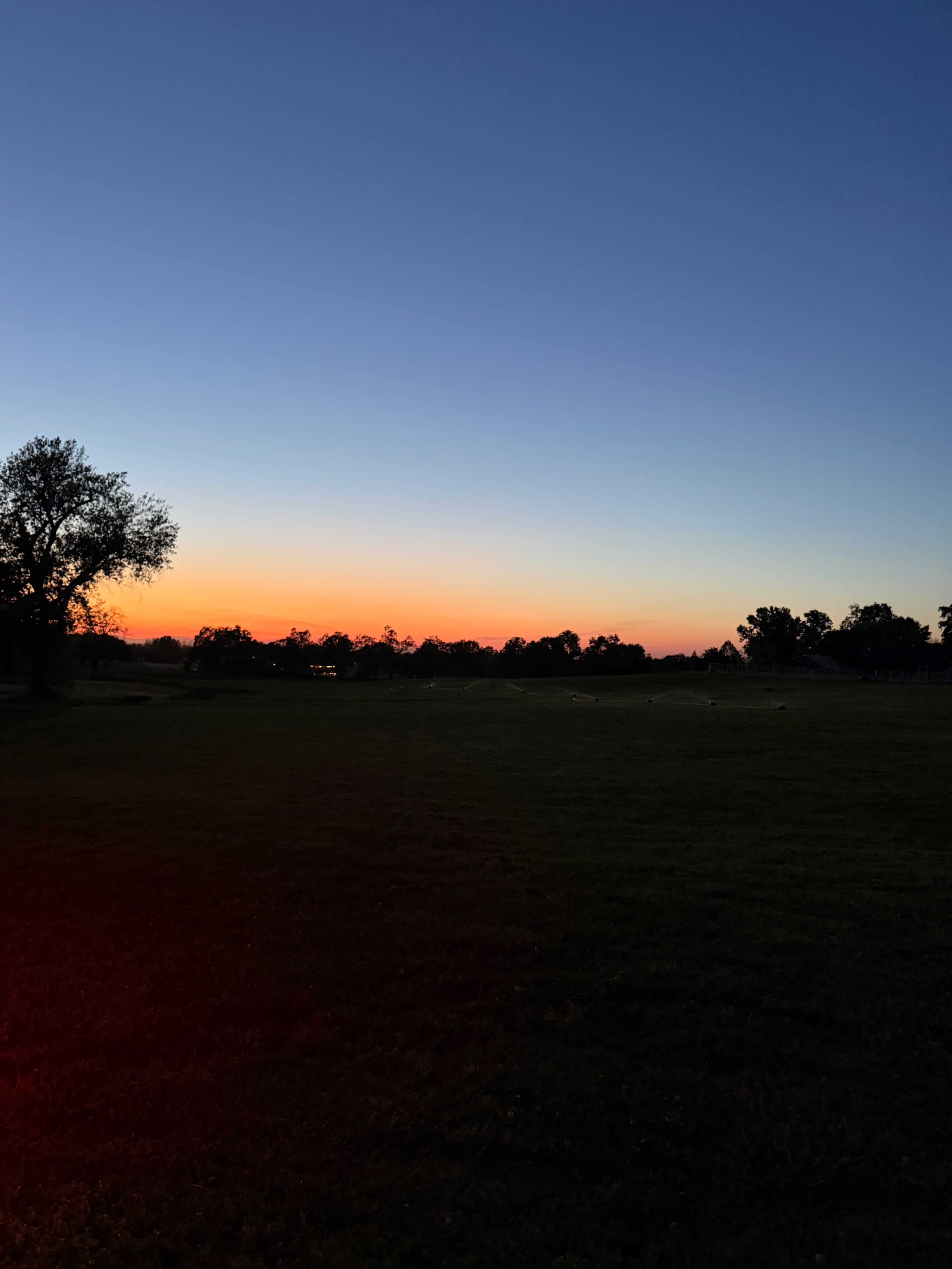 The image shows a landscape at dusk with a gradient sky transitioning from deep blue to orange along the horizon.