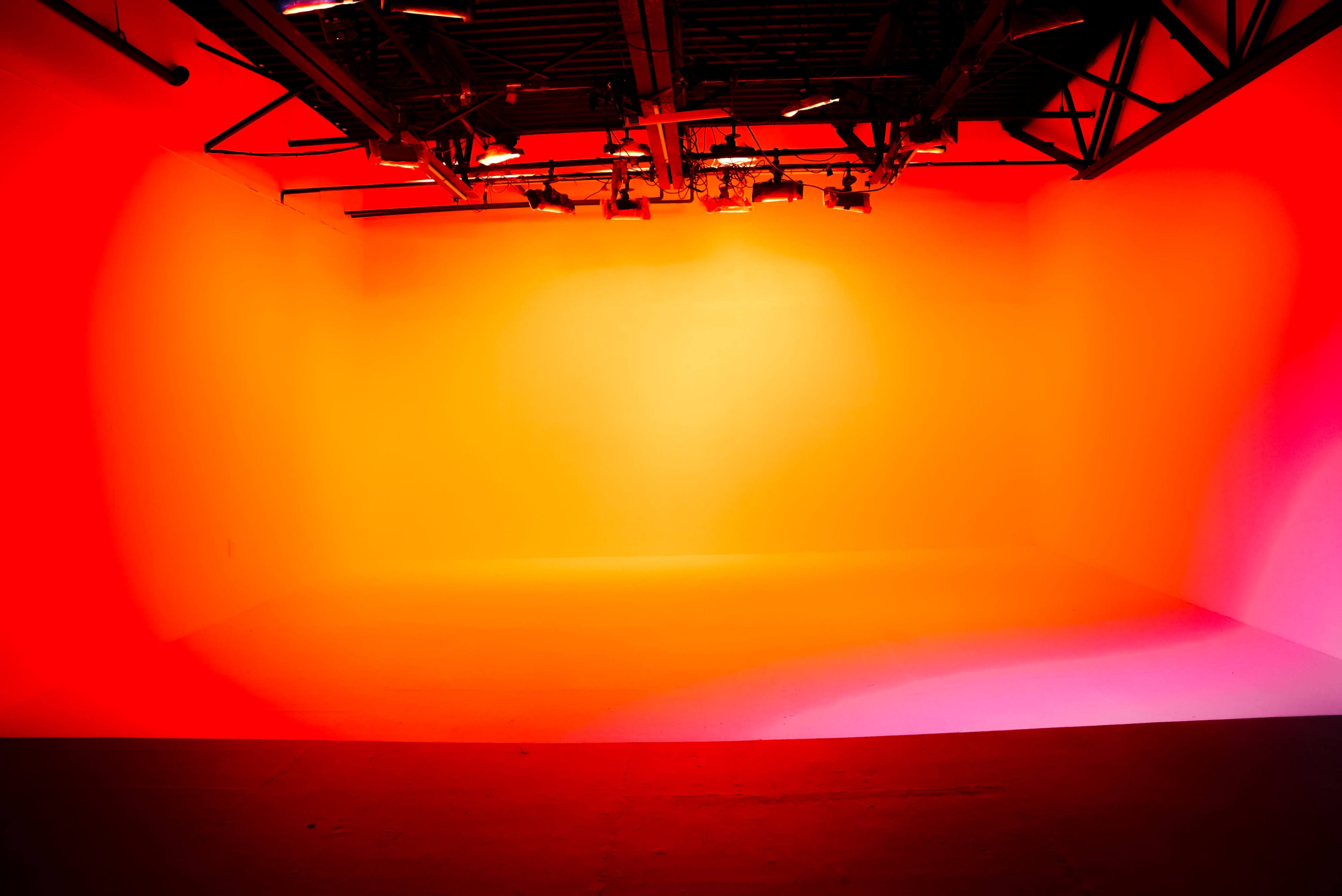 A blank studio space is illuminated with a gradient of red and orange lighting.