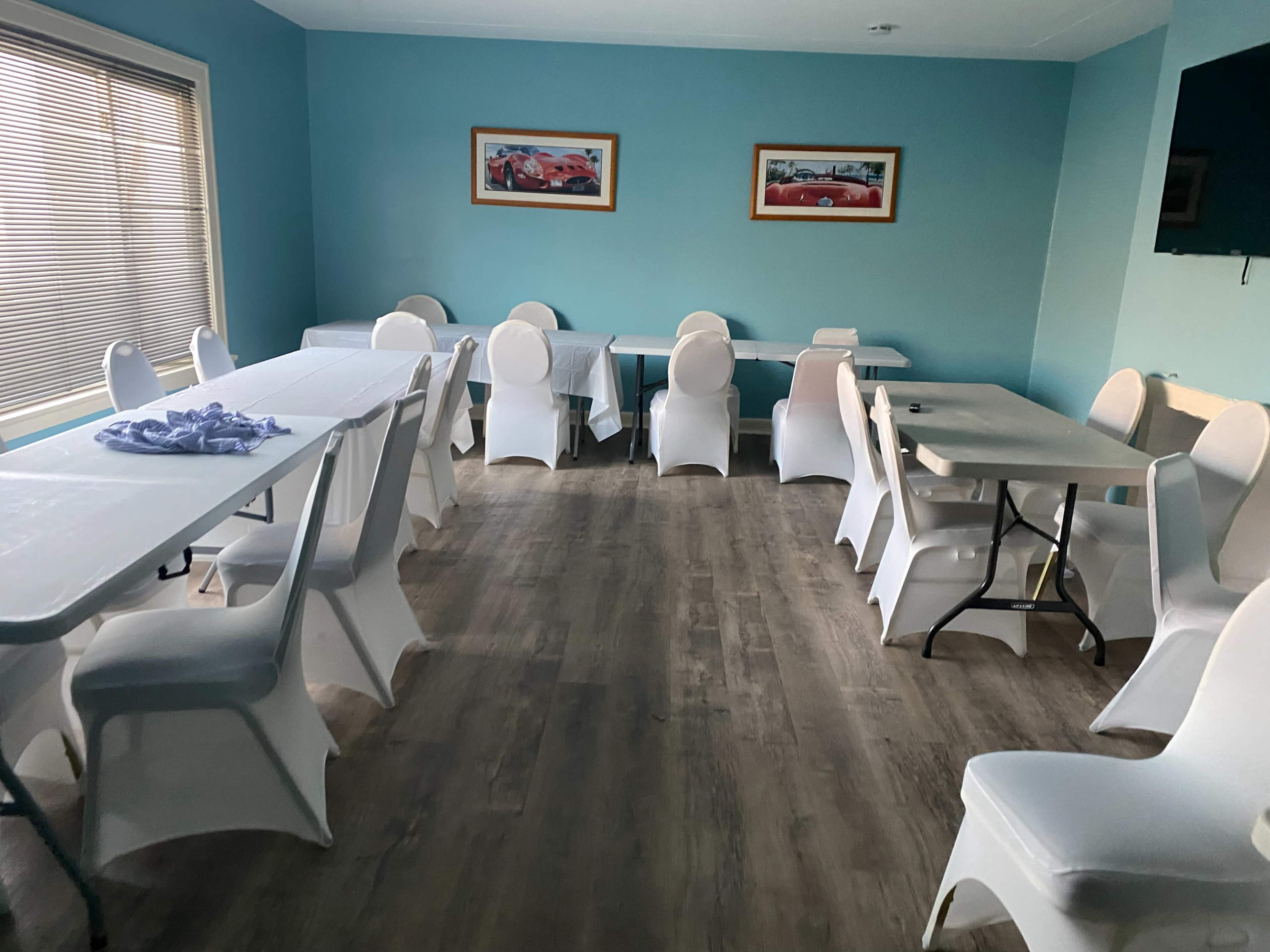 A brightly colored room with turquoise walls, containing several tables and chairs arranged in a neat layout.