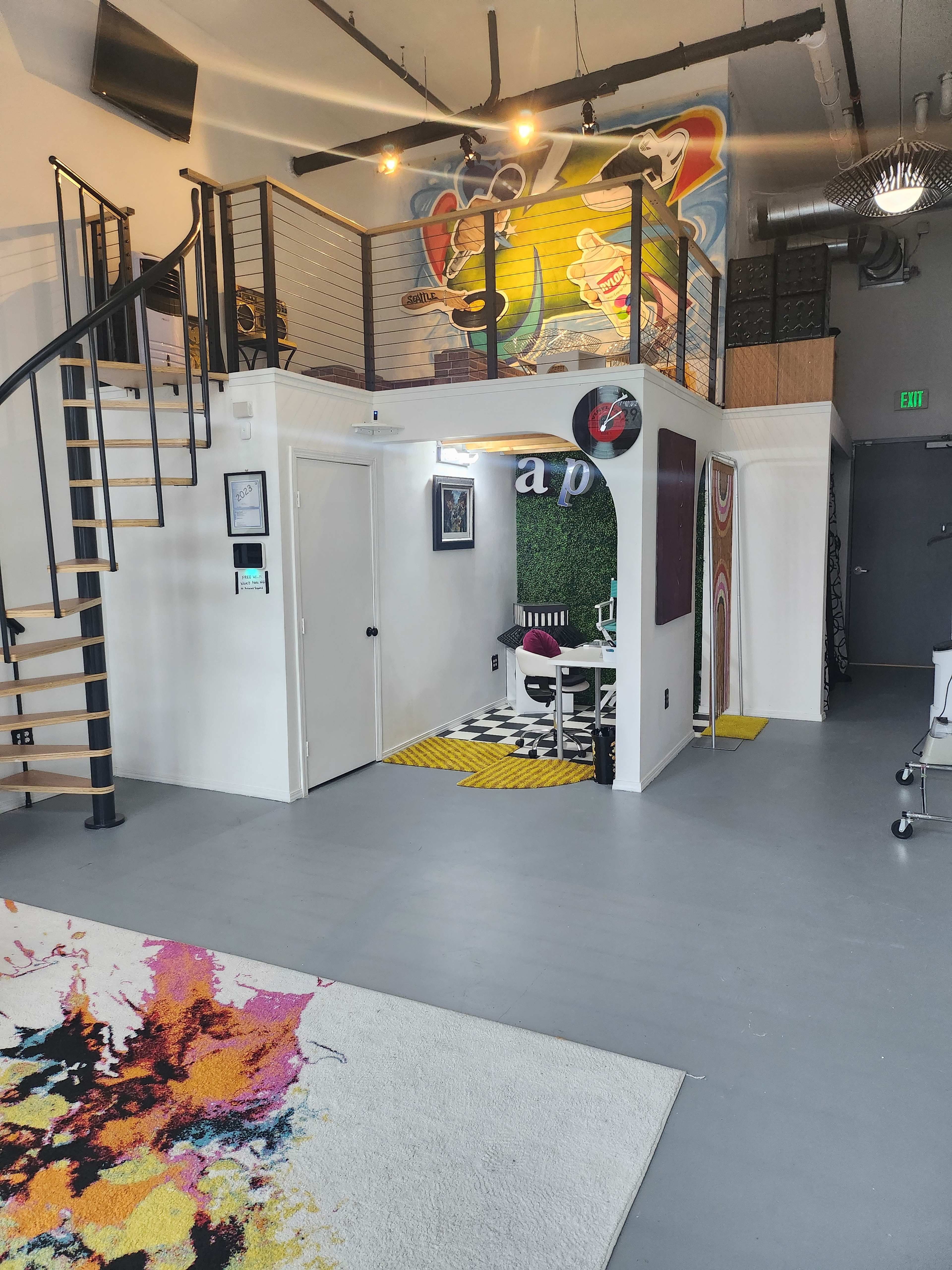 A modern, multi-level interior space featuring a spiral staircase, colorful wall art, and distinct areas defined by rugs and furniture.