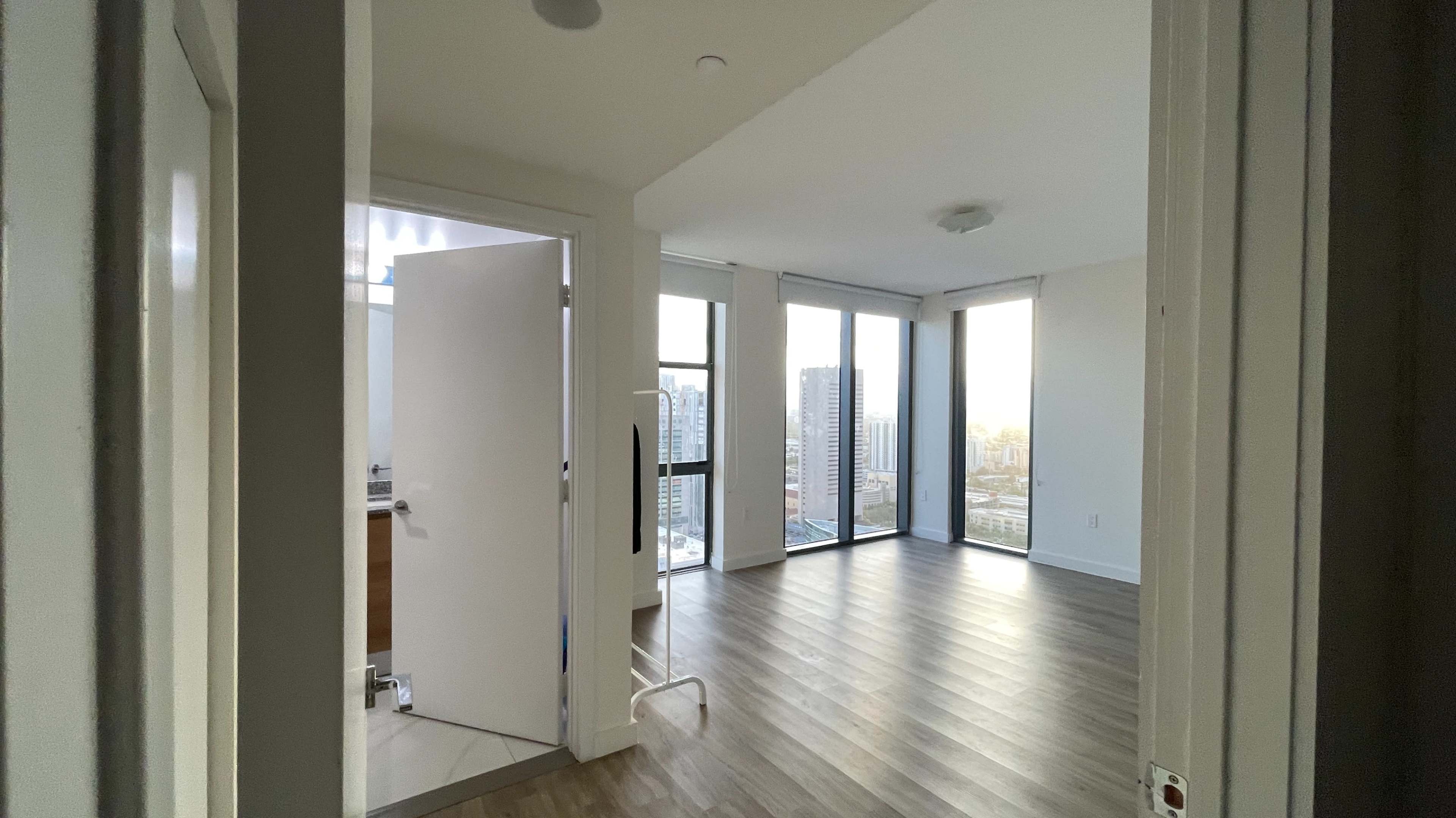 An interior view of a modern room with large windows and a door leading to a bathroom.