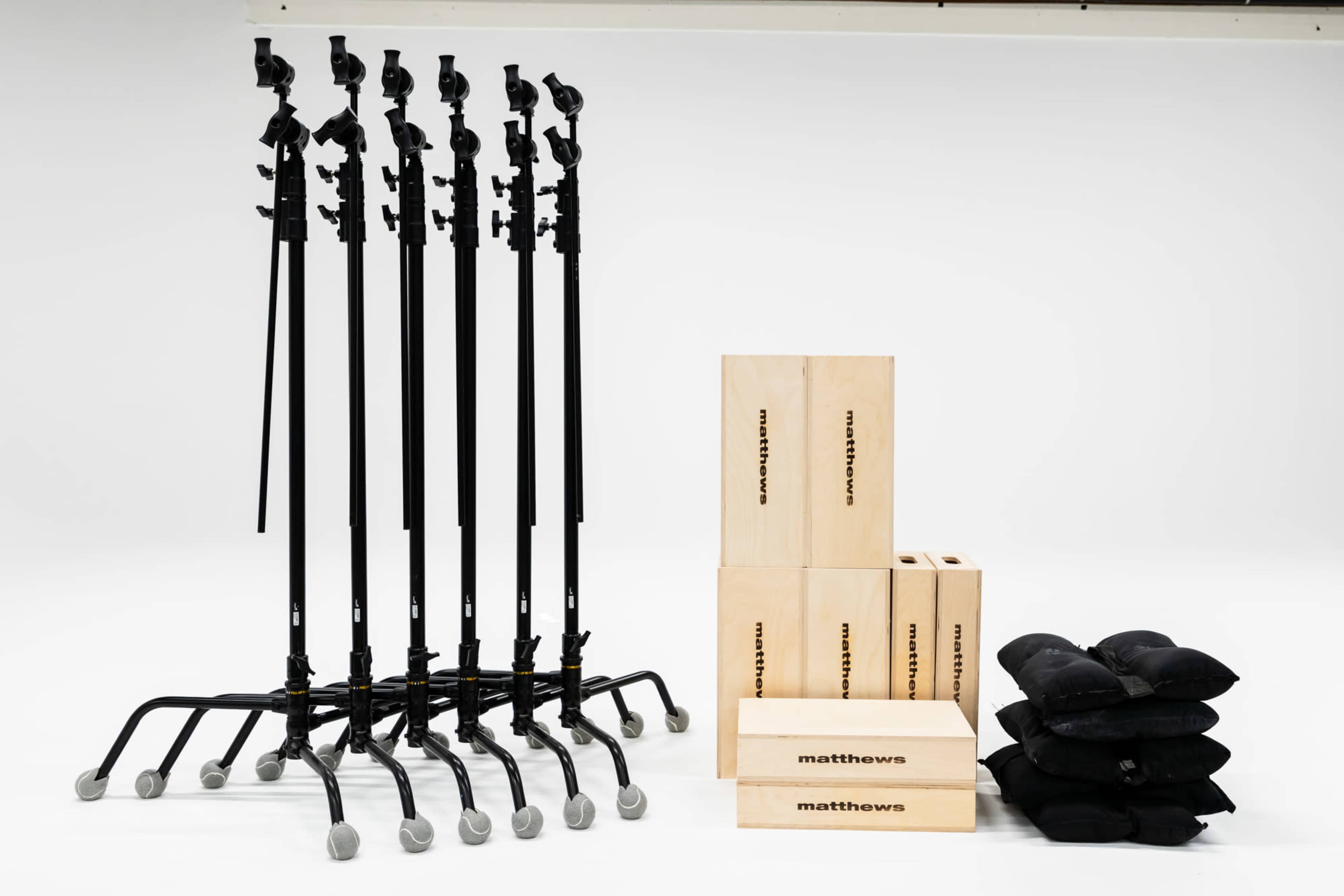 The image shows five black light stands arranged in a row beside several wooden boxes and stacked sandbags.