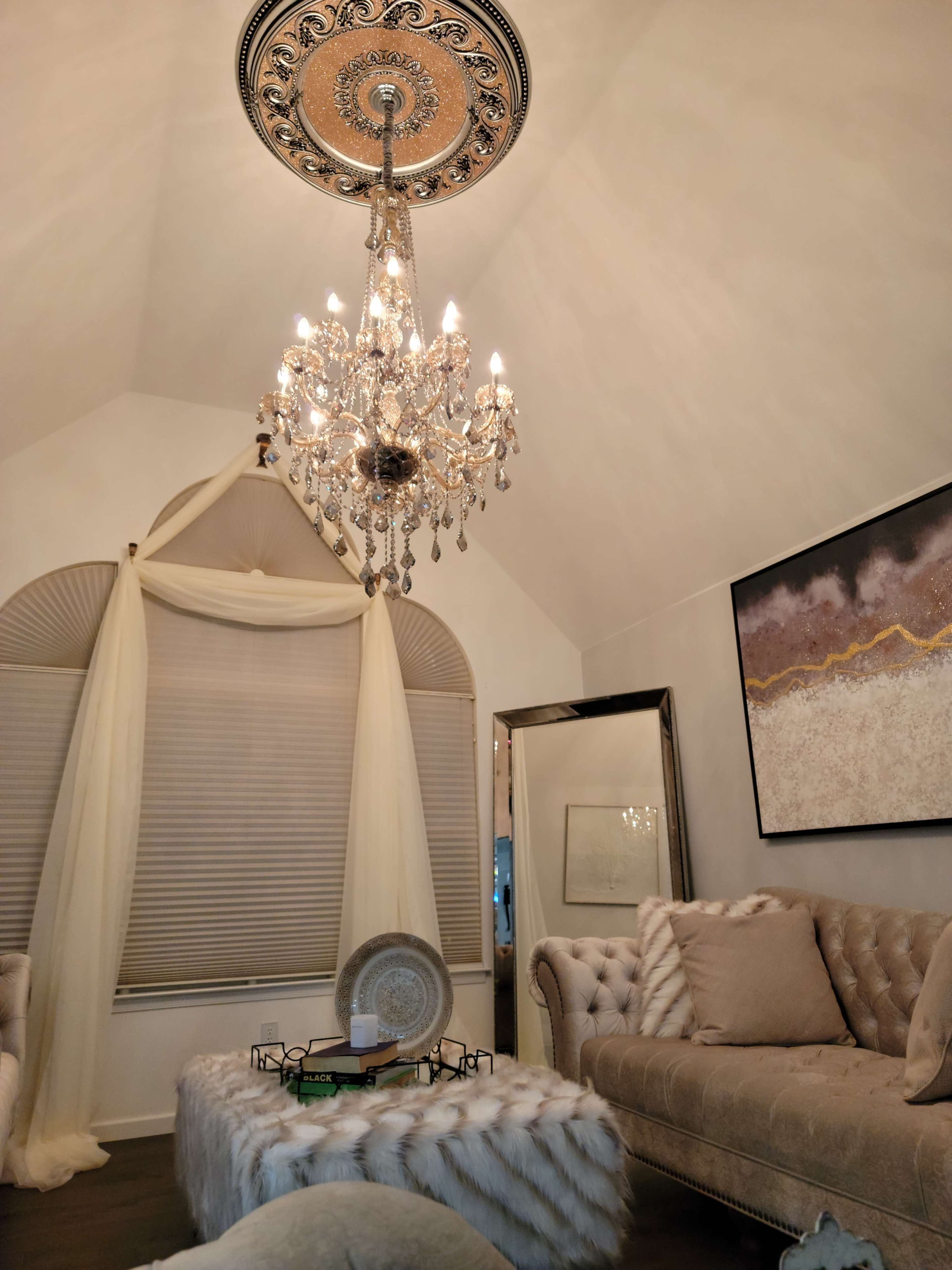 A cozy living room featuring a crystal chandelier, elegant furniture, and a decorative coffee table with books.