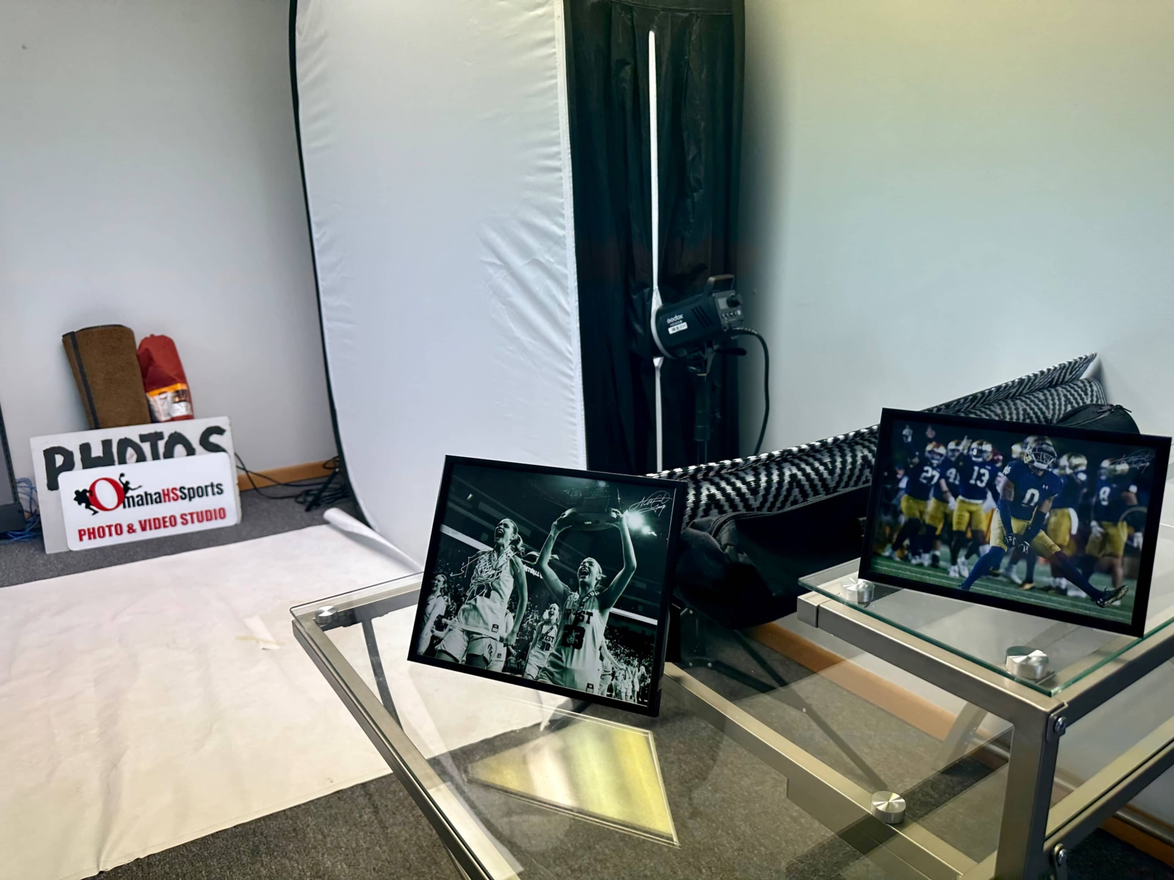 A photography studio setup is shown with two framed photos on a glass table, a backdrop, and equipment visible in the background.