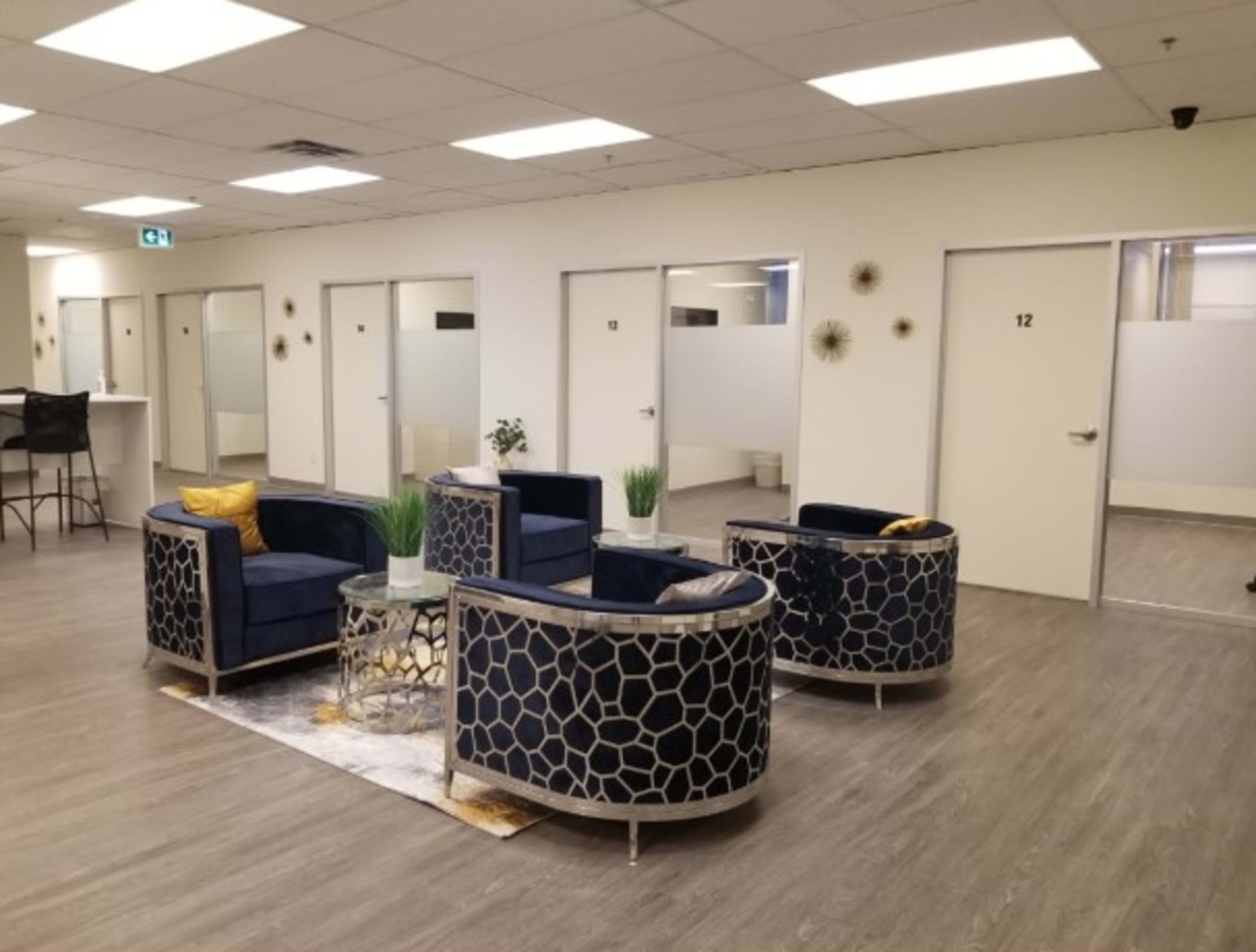 A waiting area with two circular sofas, a glass coffee table, and several closed office doors in a well-lit space.