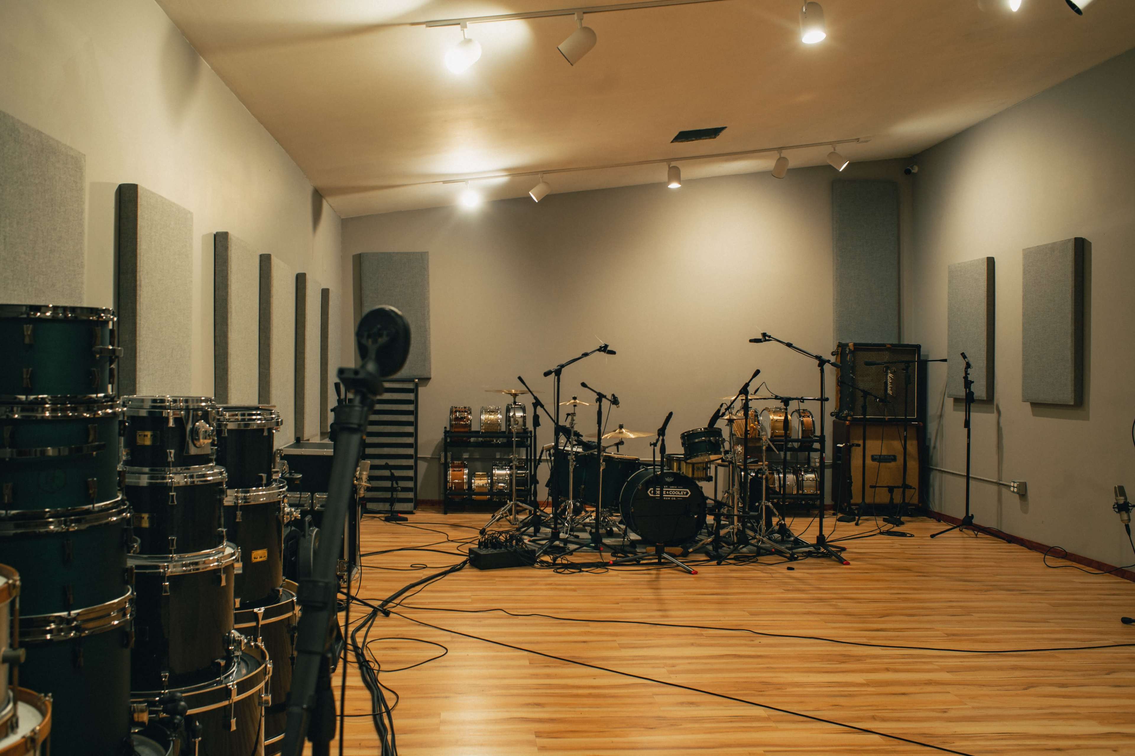 A recording studio with various instruments set up, including a drum kit and sound equipment, surrounded by padded walls.