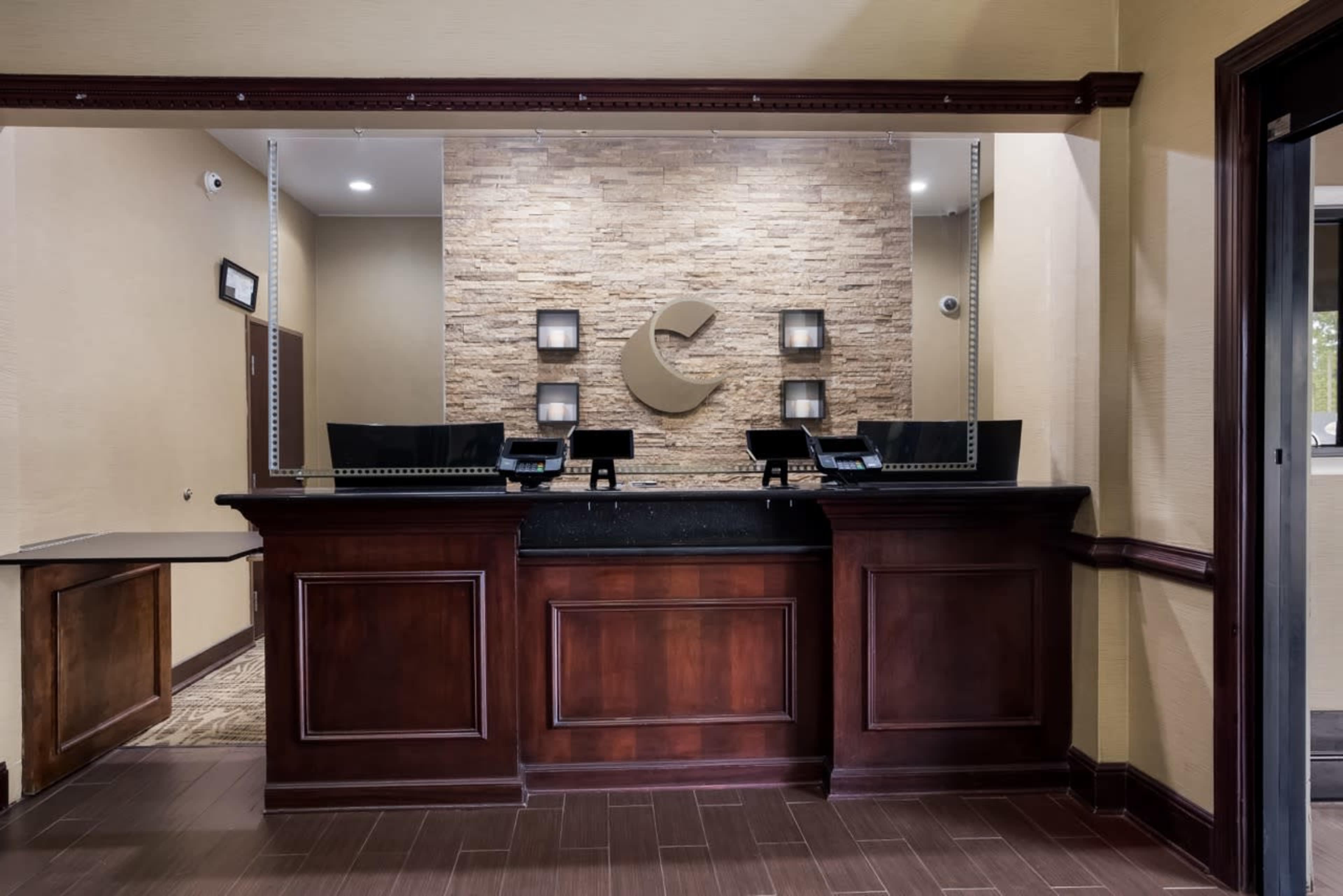The image shows a reception area with a wooden front desk, stone wall accents, and modern lighting fixtures.
