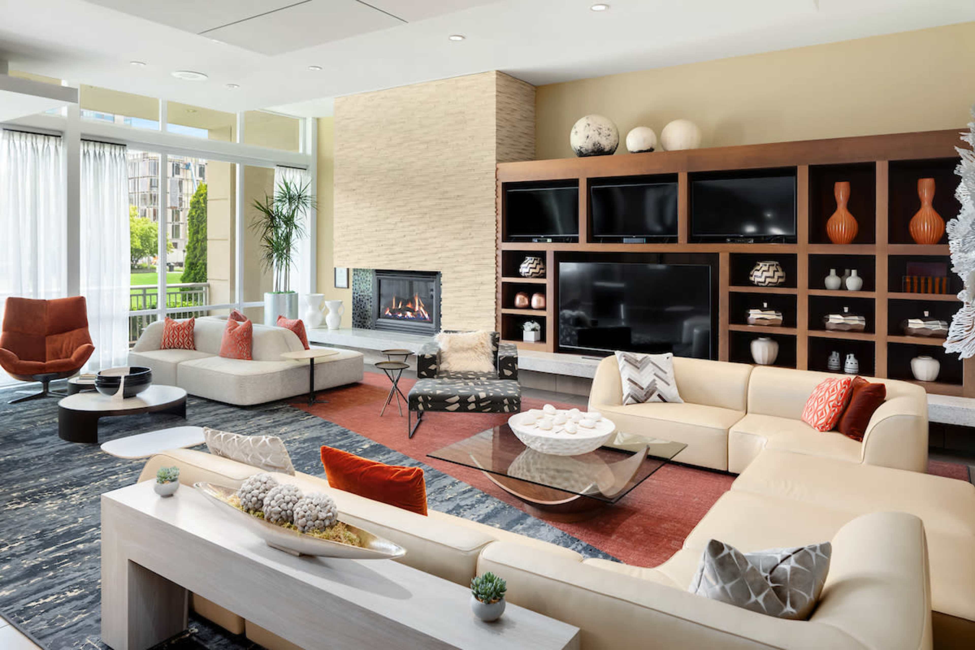 A modern living room with a large sectional sofa, a coffee table, a fireplace, and decorative shelves containing vases and other items.