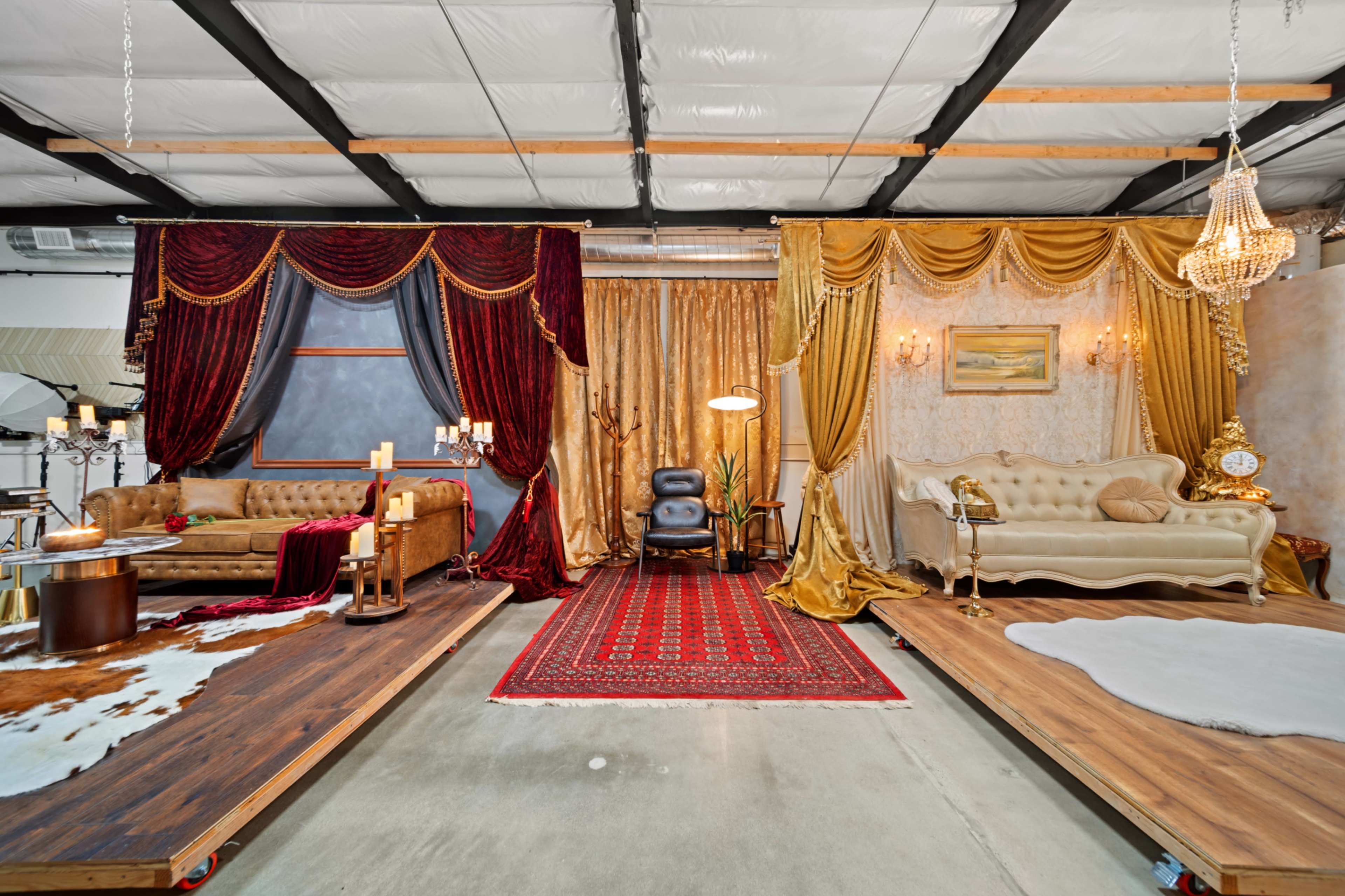 The image shows a split interior space featuring two distinct lounge areas, one adorned with red velvet drapes and ornate décor, and the other with gold curtains and elegant furniture.