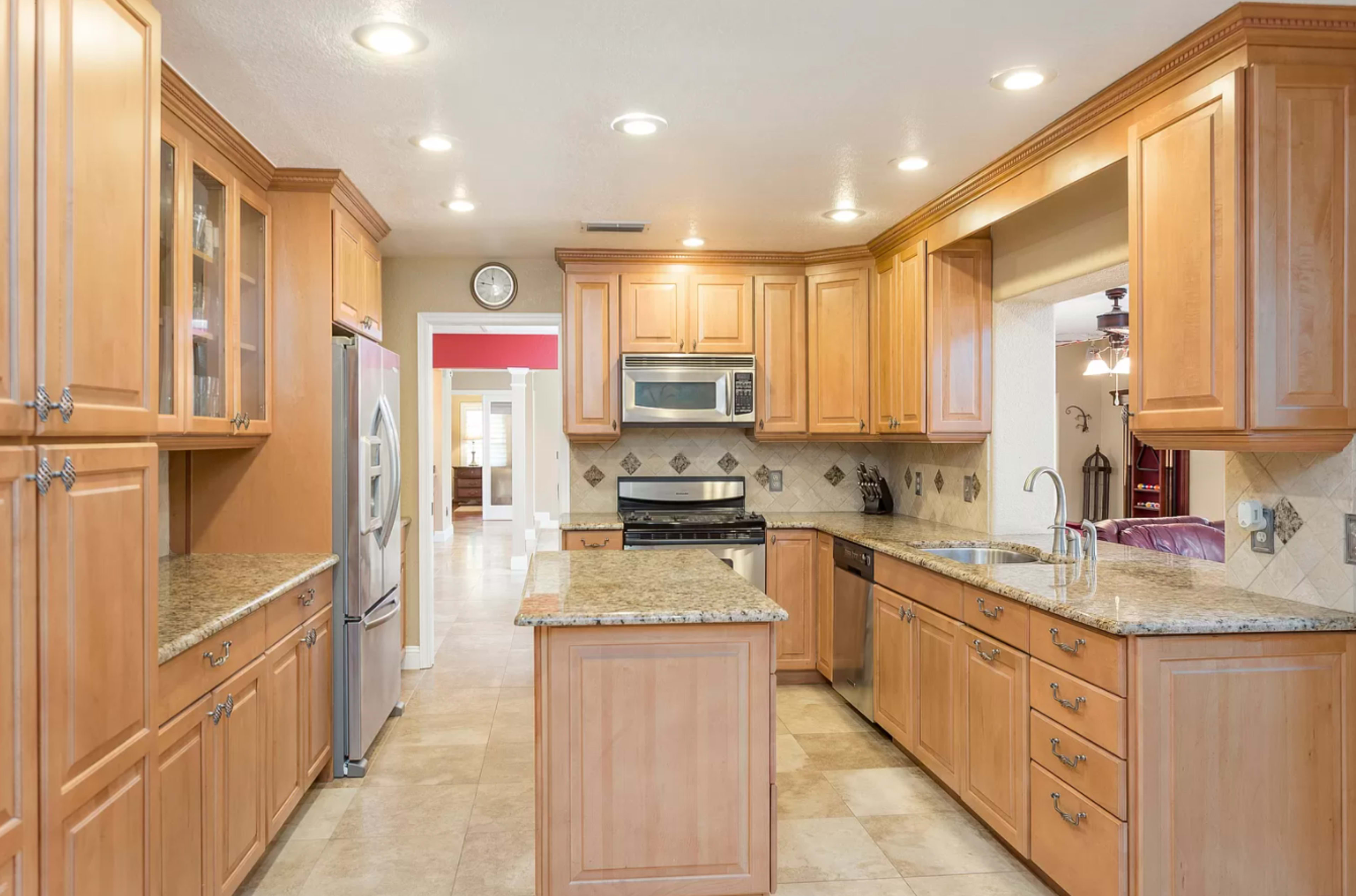 A kitchen featuring wooden cabinets, granite countertops, and stainless steel appliances, with an island in the center.