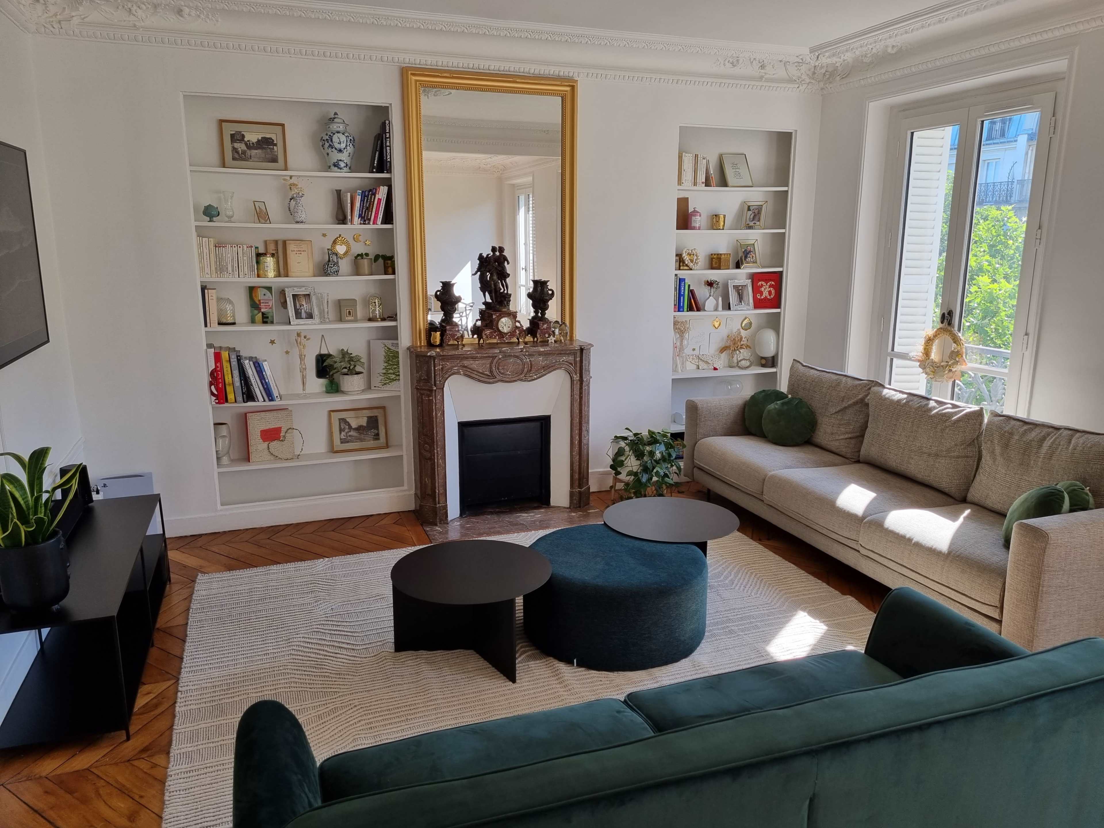 A well-furnished living room featuring a fireplace, bookshelves filled with decorative items, and a mix of modern and classic furniture.