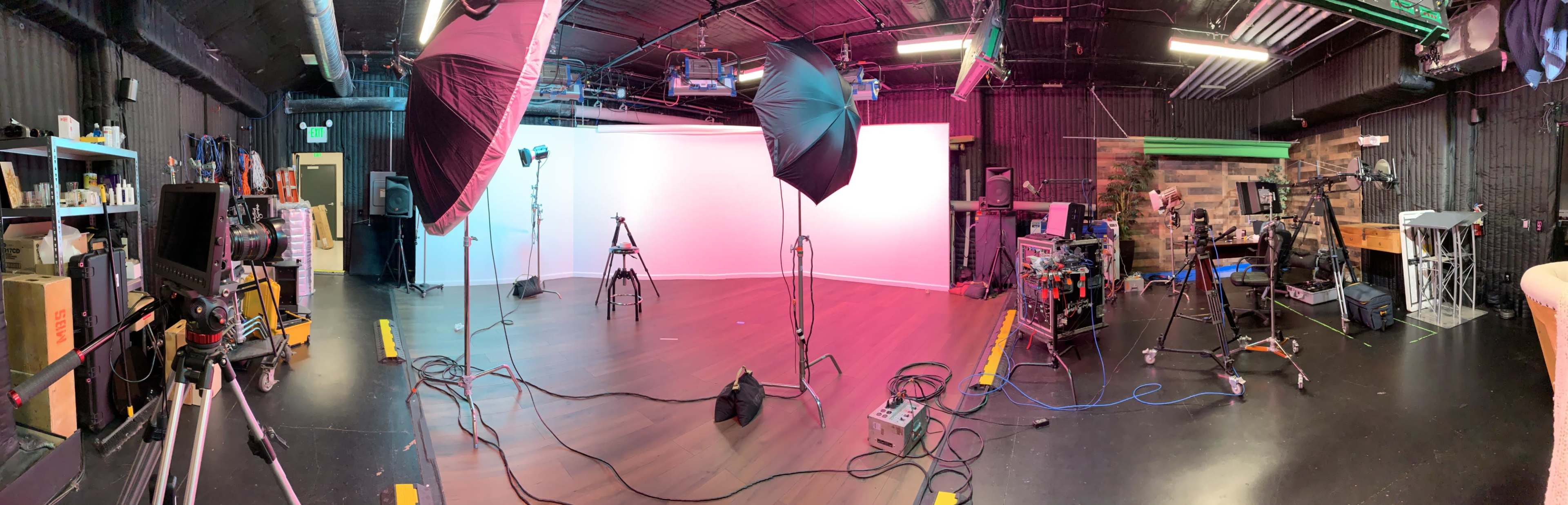 A photography studio equipped with lighting equipment, cameras, and various props arranged around a central white backdrop.