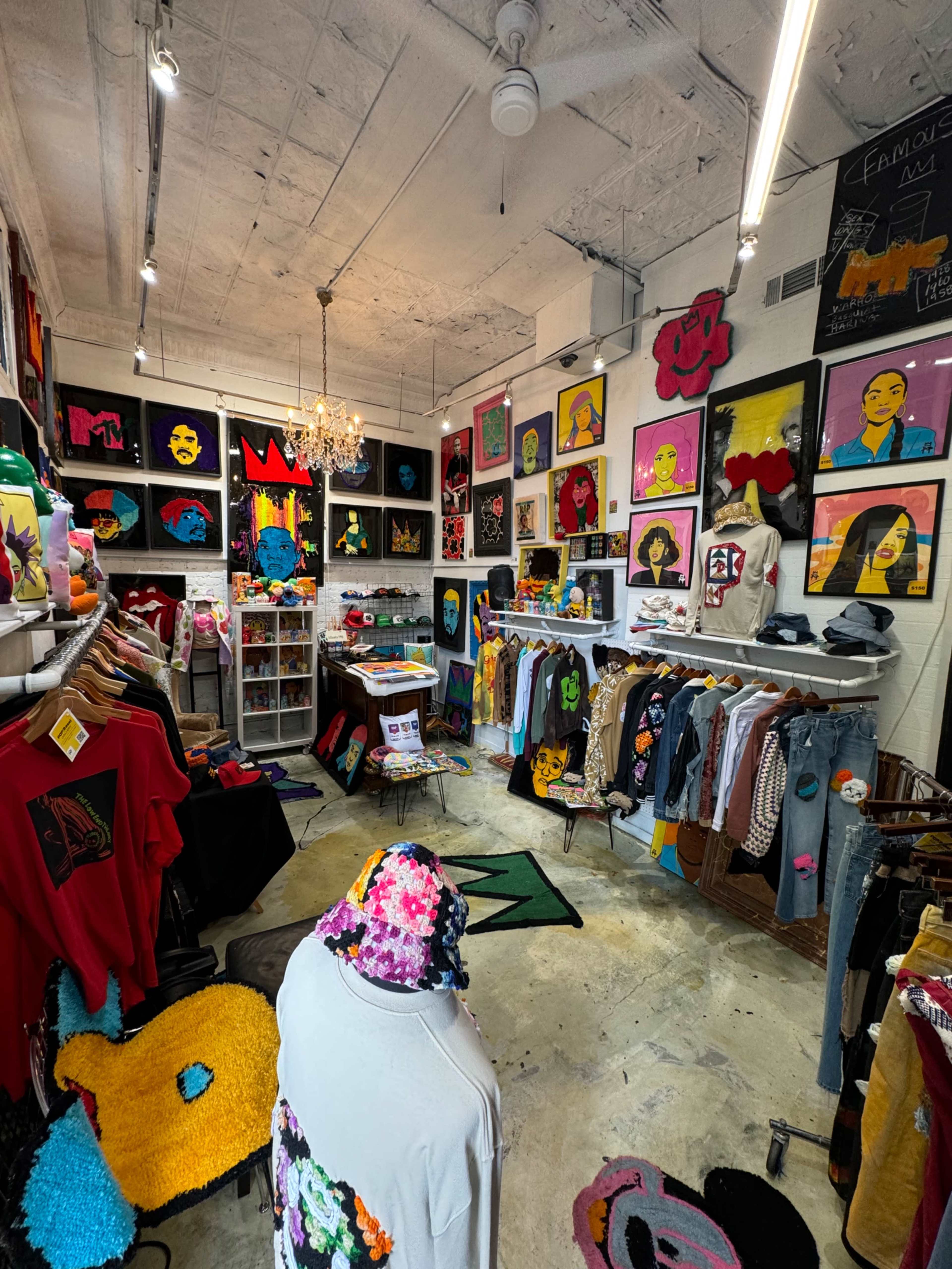 The image shows a brightly colored retail store displaying various clothing items and artwork on the walls.