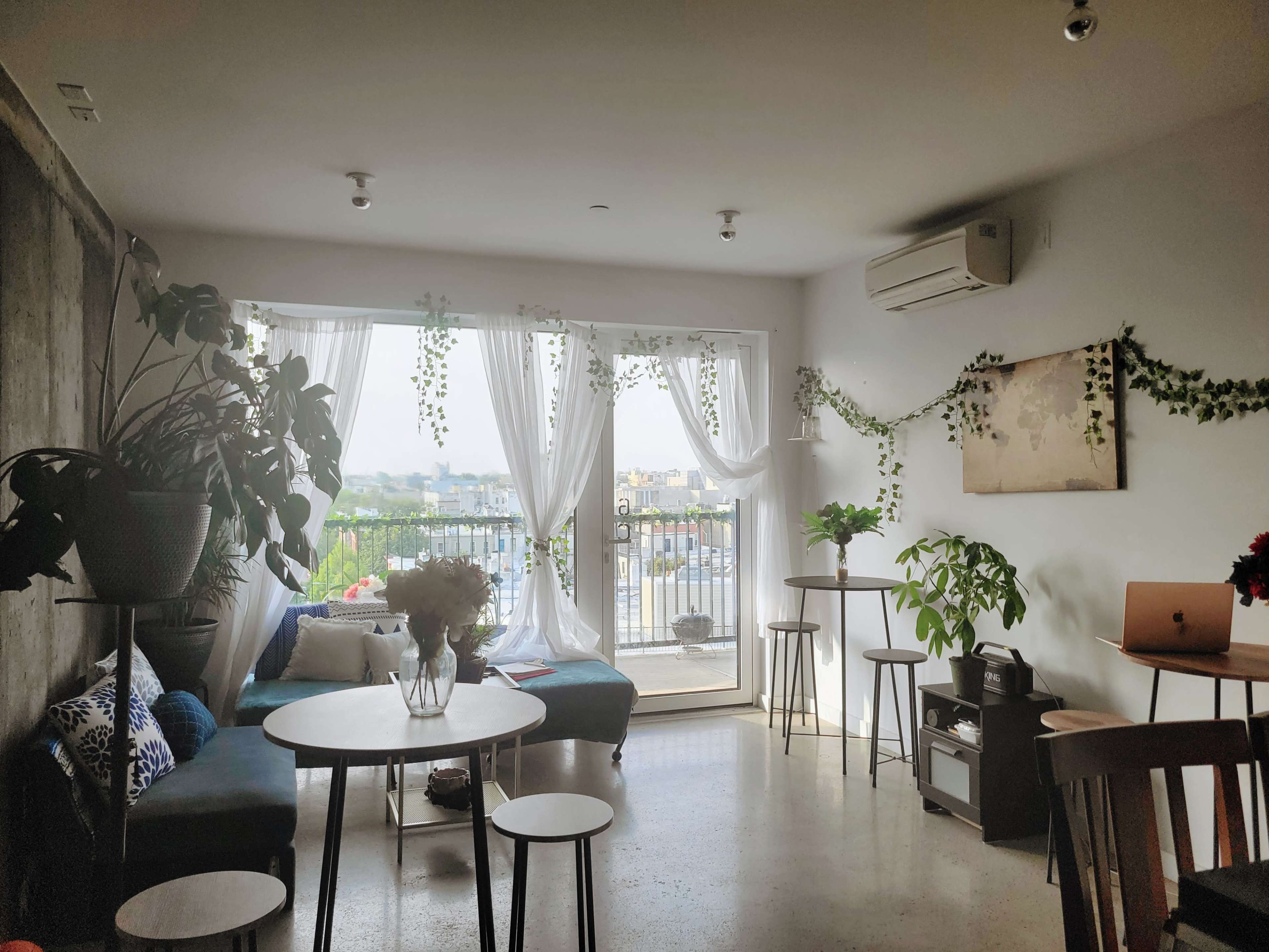 A cozy interior space with plants, seating areas, and large windows overlooking a view.