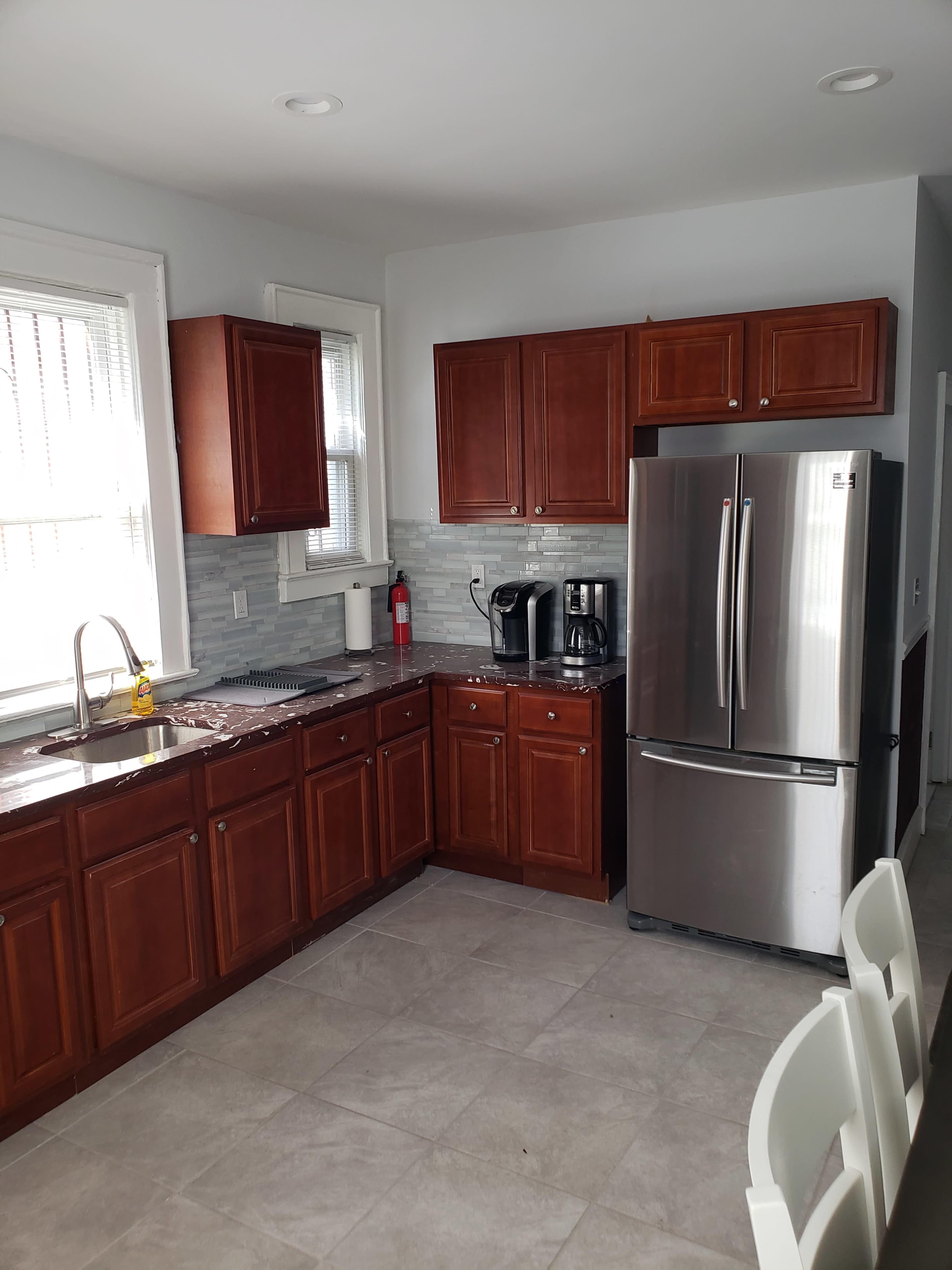 The kitchen features dark wood cabinets, stainless steel appliances, and a grey tile backsplash.