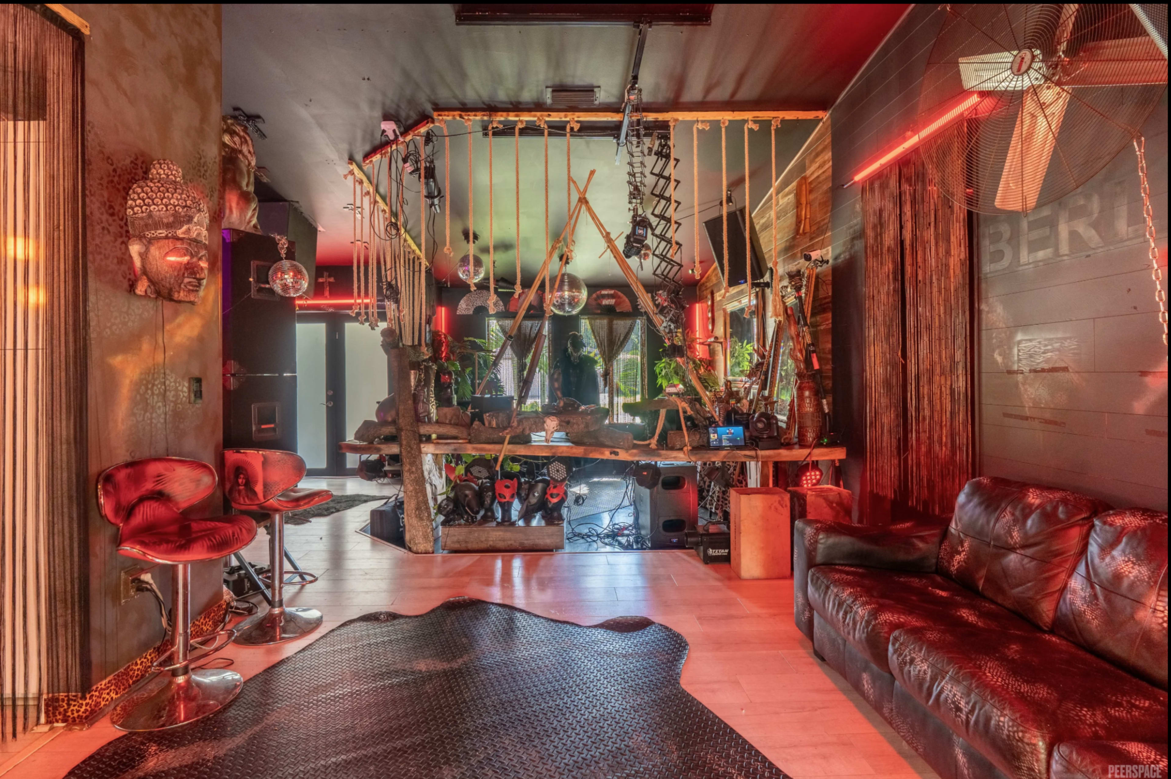 The image shows a modern, eclectic interior space featuring a mix of unique decor, a bar area with stools, and an inviting seating arrangement.