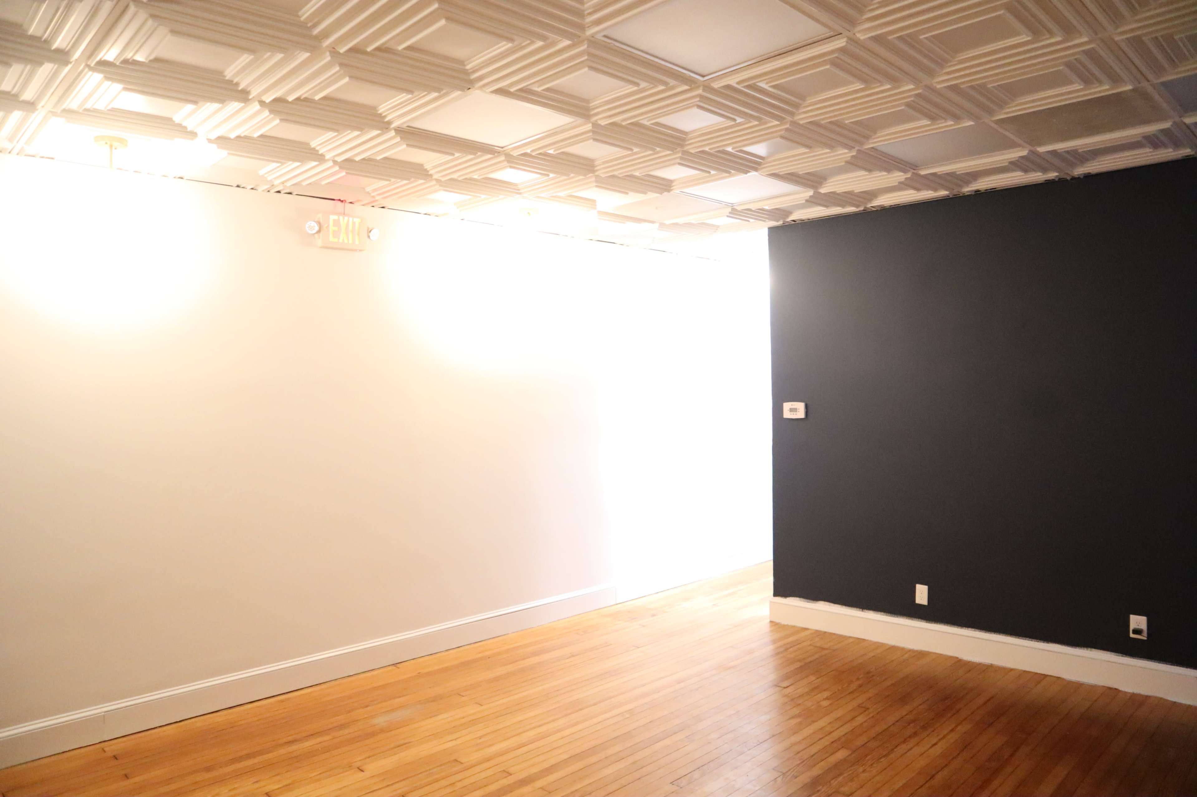 The scene shows a room with a textured ceiling and one white wall adjacent to a dark blue wall, featuring wooden flooring and a bright light source at the far end.
