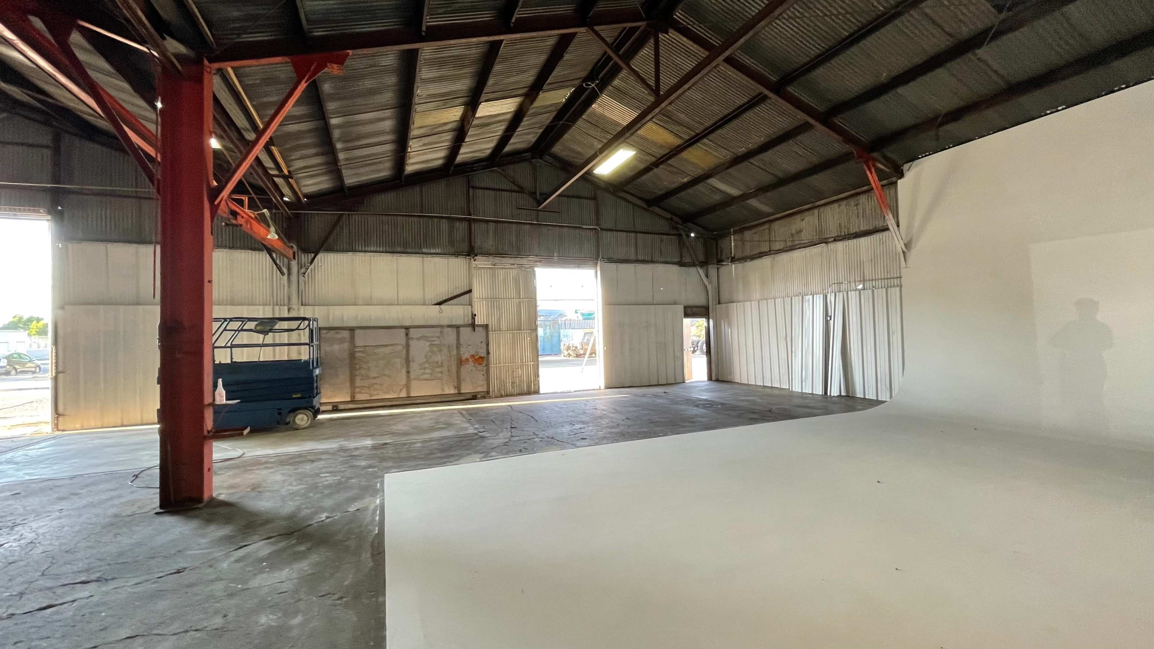 A large, empty industrial warehouse with a white background and metal support beams.