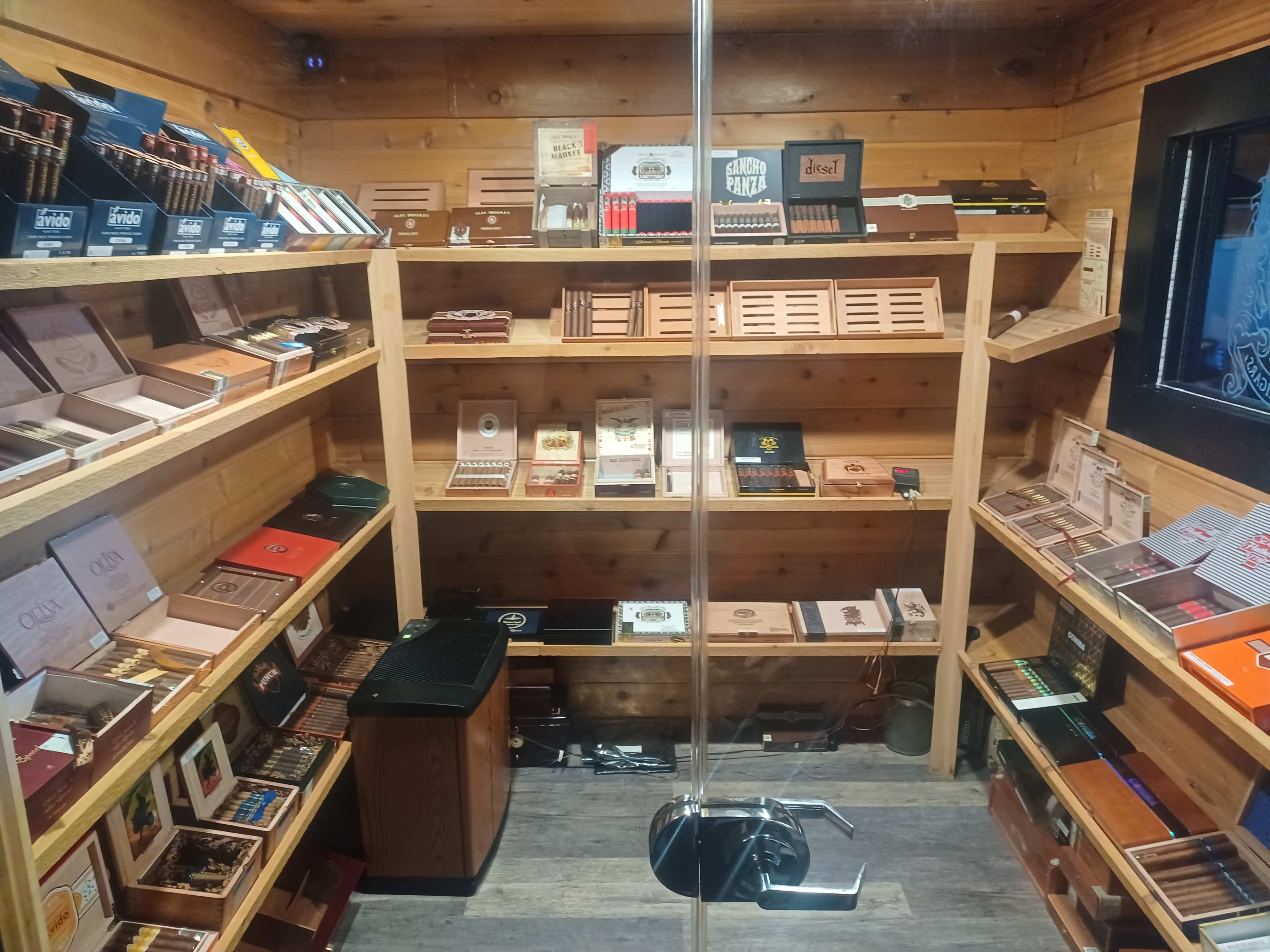 An indoor display of various cigar boxes neatly organized on wooden shelves in a private storage area.