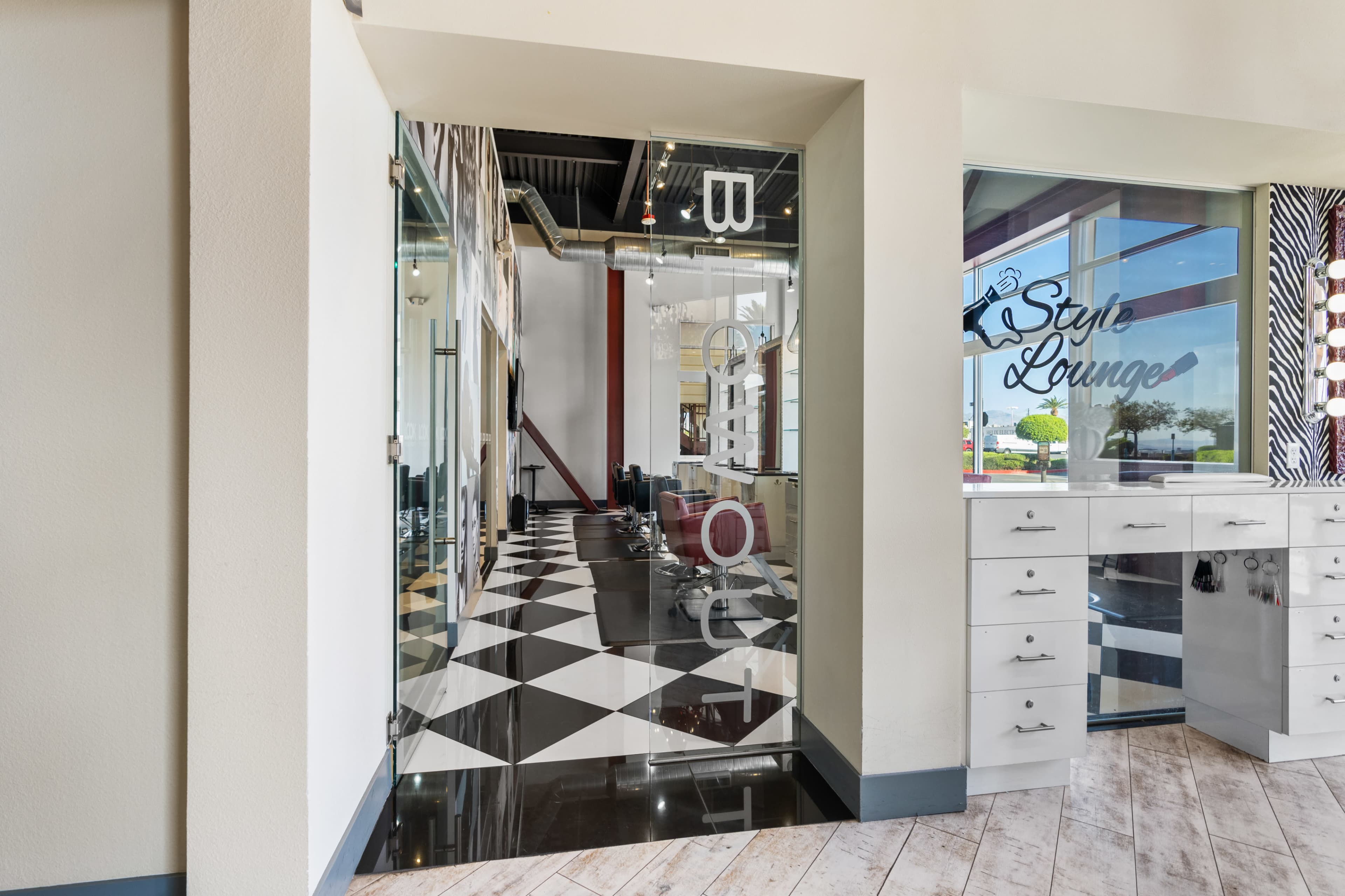 The entrance to a salon or style lounge featuring a black and white checkered floor and modern decor.