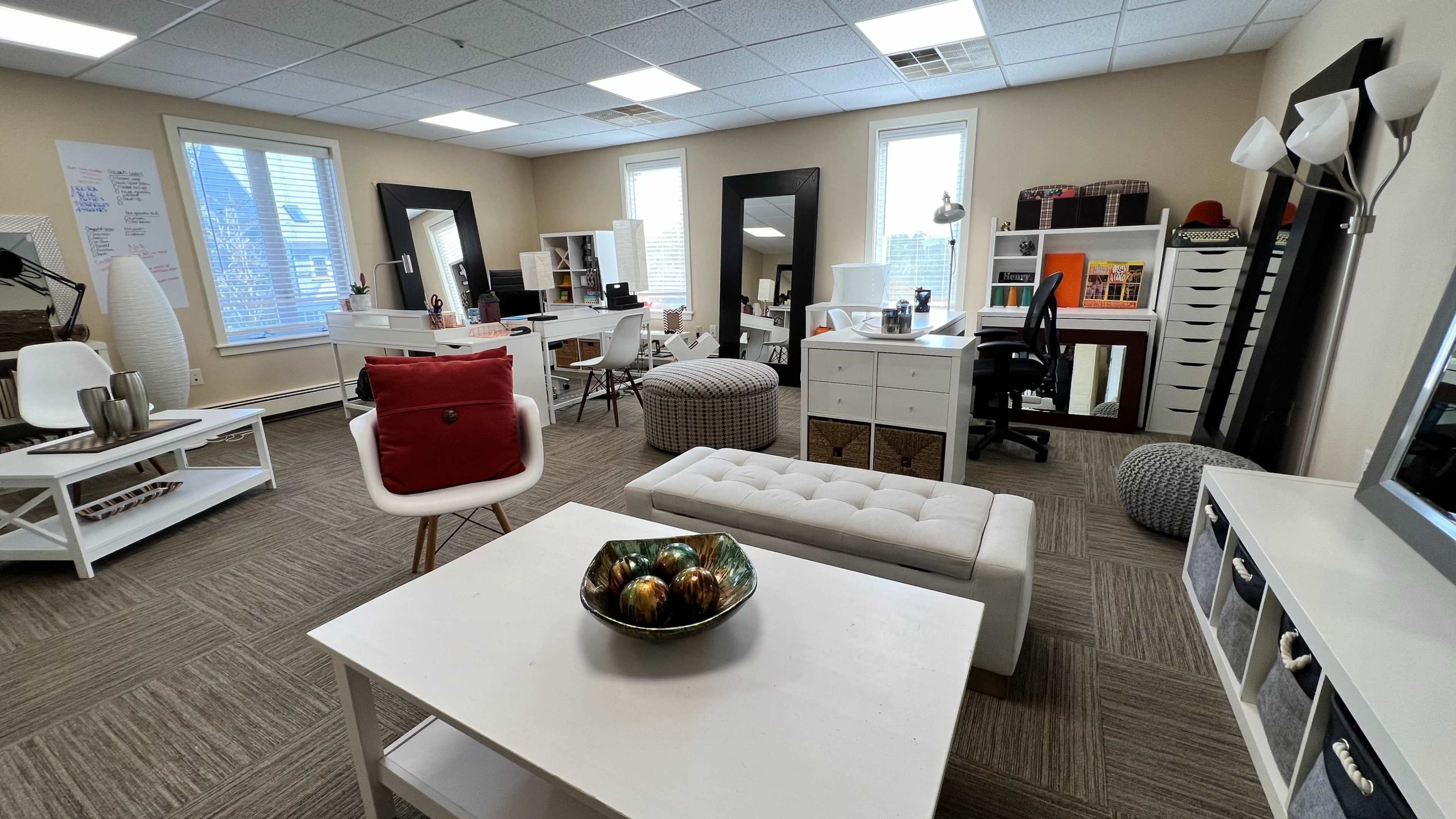 A spacious office environment with multiple desks, storage units, and decorative items arranged throughout the room.