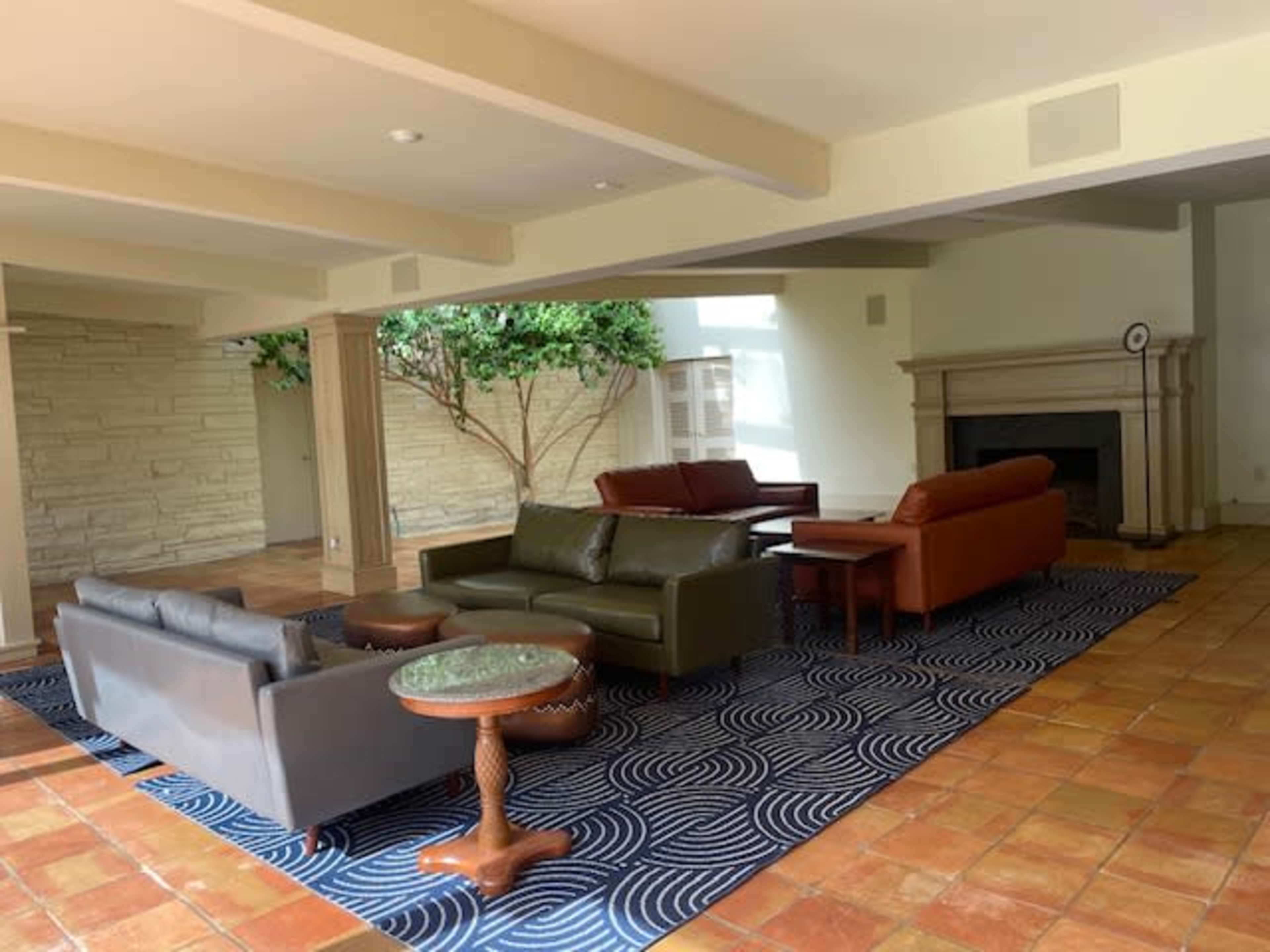 A spacious living area with two sofas, a coffee table, and a wall-mounted clock, featuring tiled flooring and a large window.