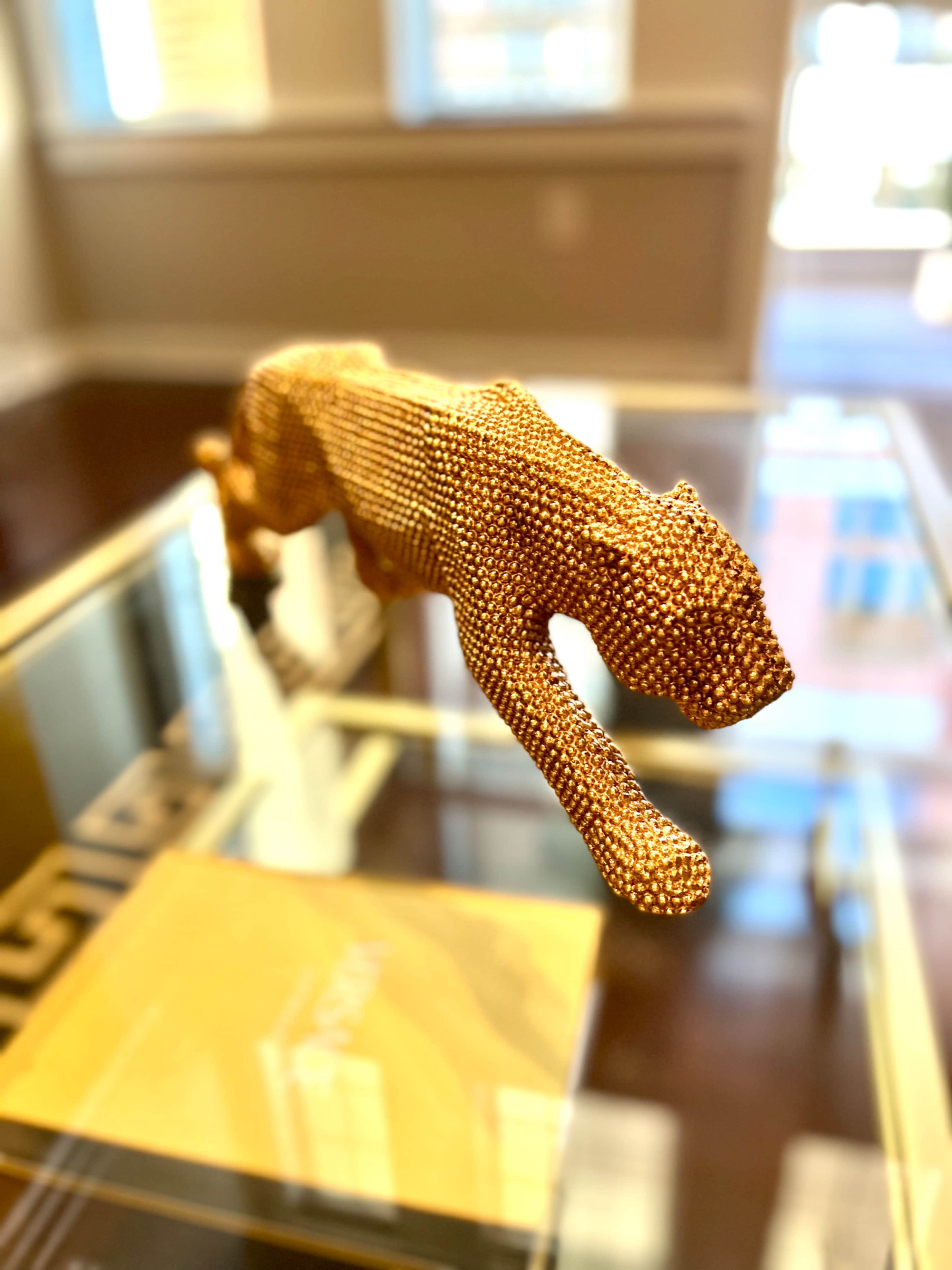 A bronze sculpture of a prowling cat is displayed on a glass table.