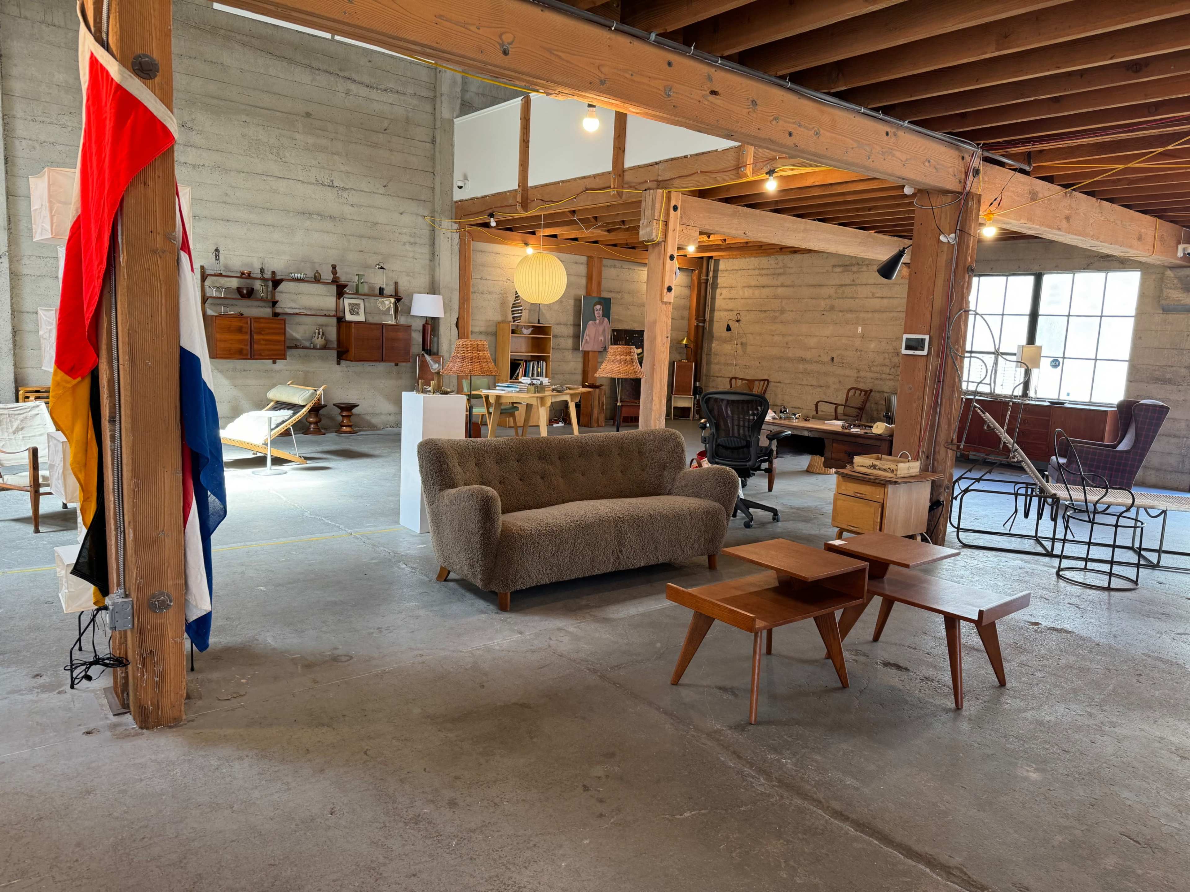 A spacious, well-lit interior with mid-century furniture, including a sofa, tables, and various decorative elements.