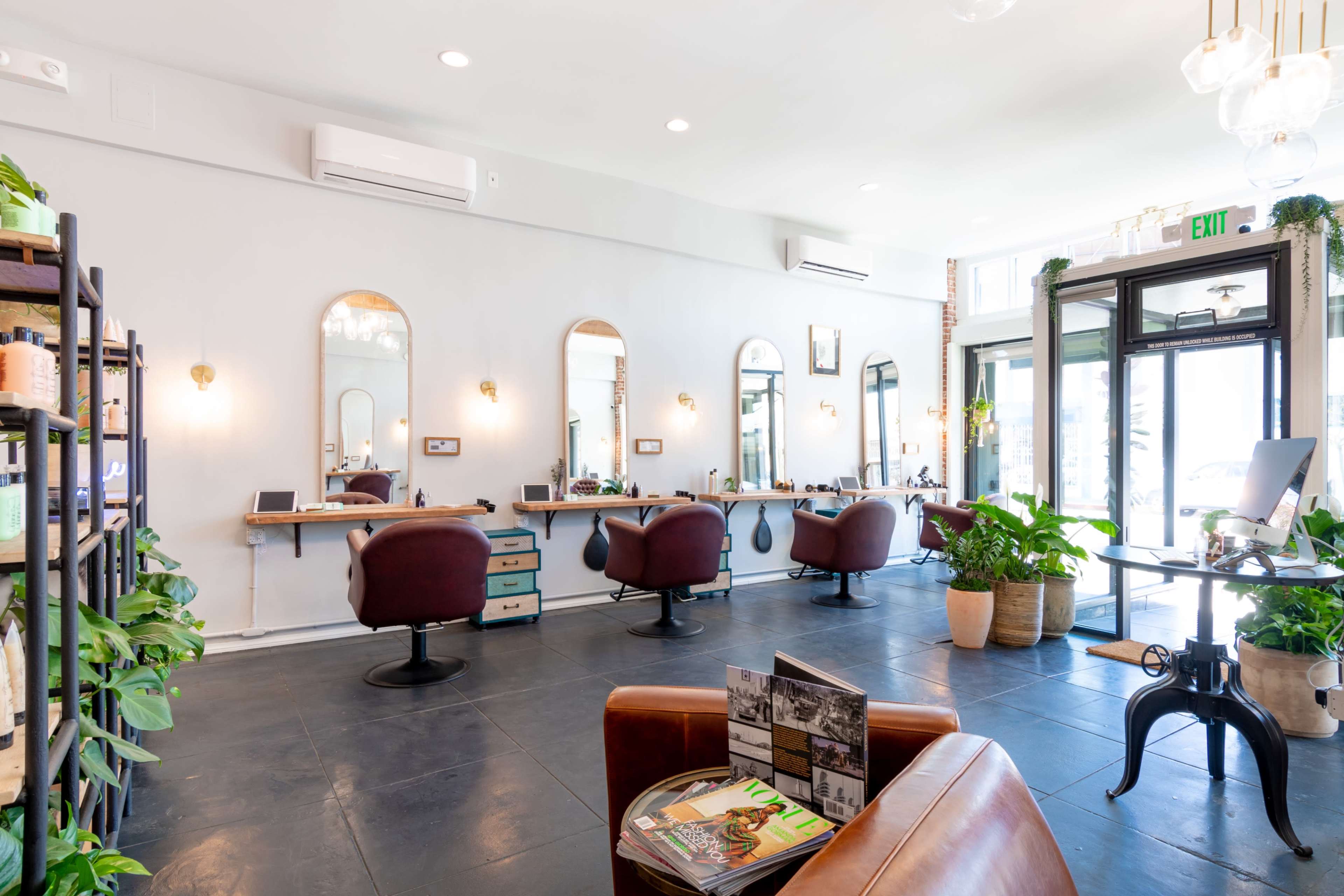Large open gallery like salon space with brick and wood beams, high ceilings and many plants. Image in Central LA, Los Angeles, CA