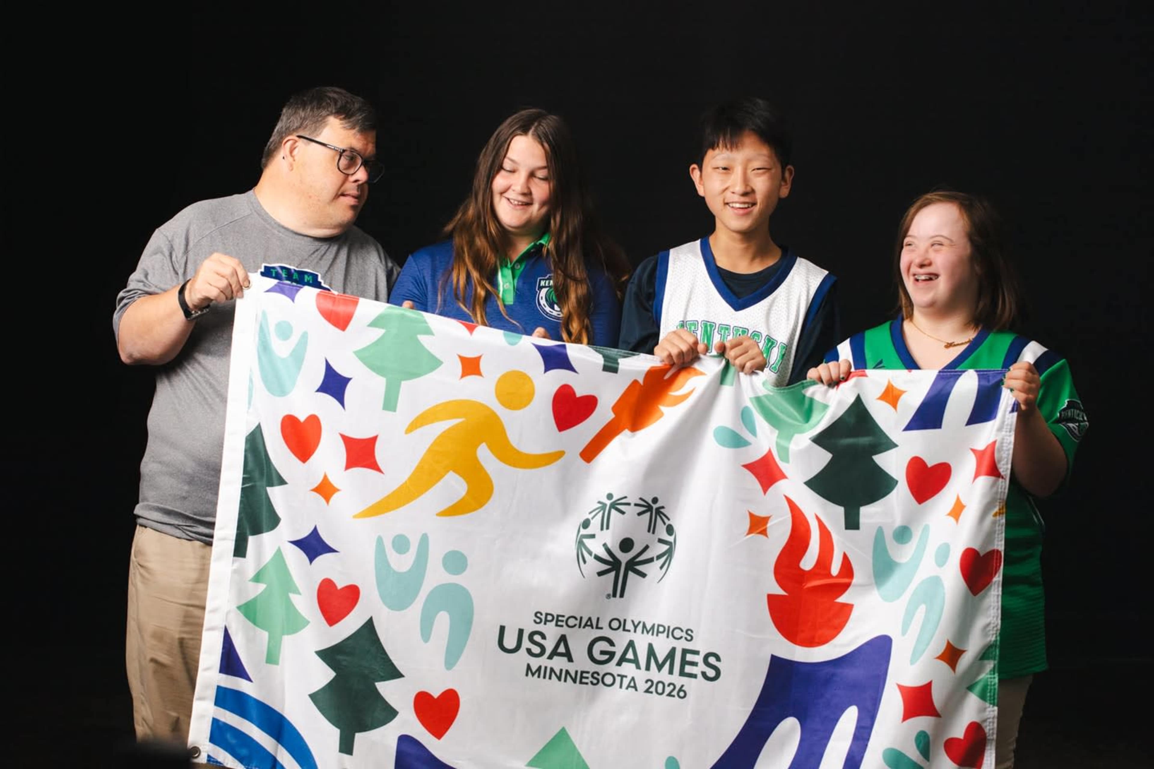 Four individuals hold a colorful banner representing the Special Olympics USA Games, scheduled to take place in Minnesota in 2026.